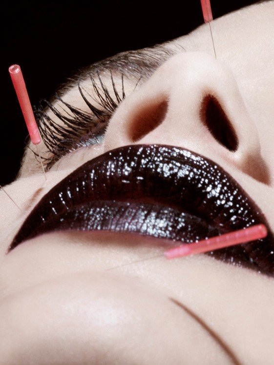 Beauty and pain, a photograph by Carlos Lumiere, left side of the image, strong light and acupuncture needles across the face.