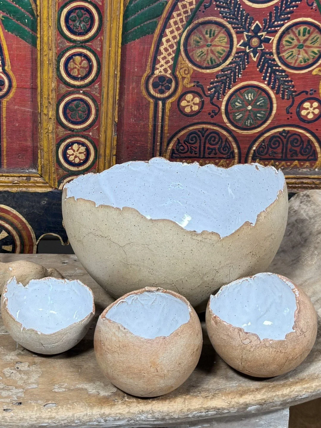 Group of small handmade crackle bowls by ceramic Artist Nupur Narain DeTar, displayed with African furniture.