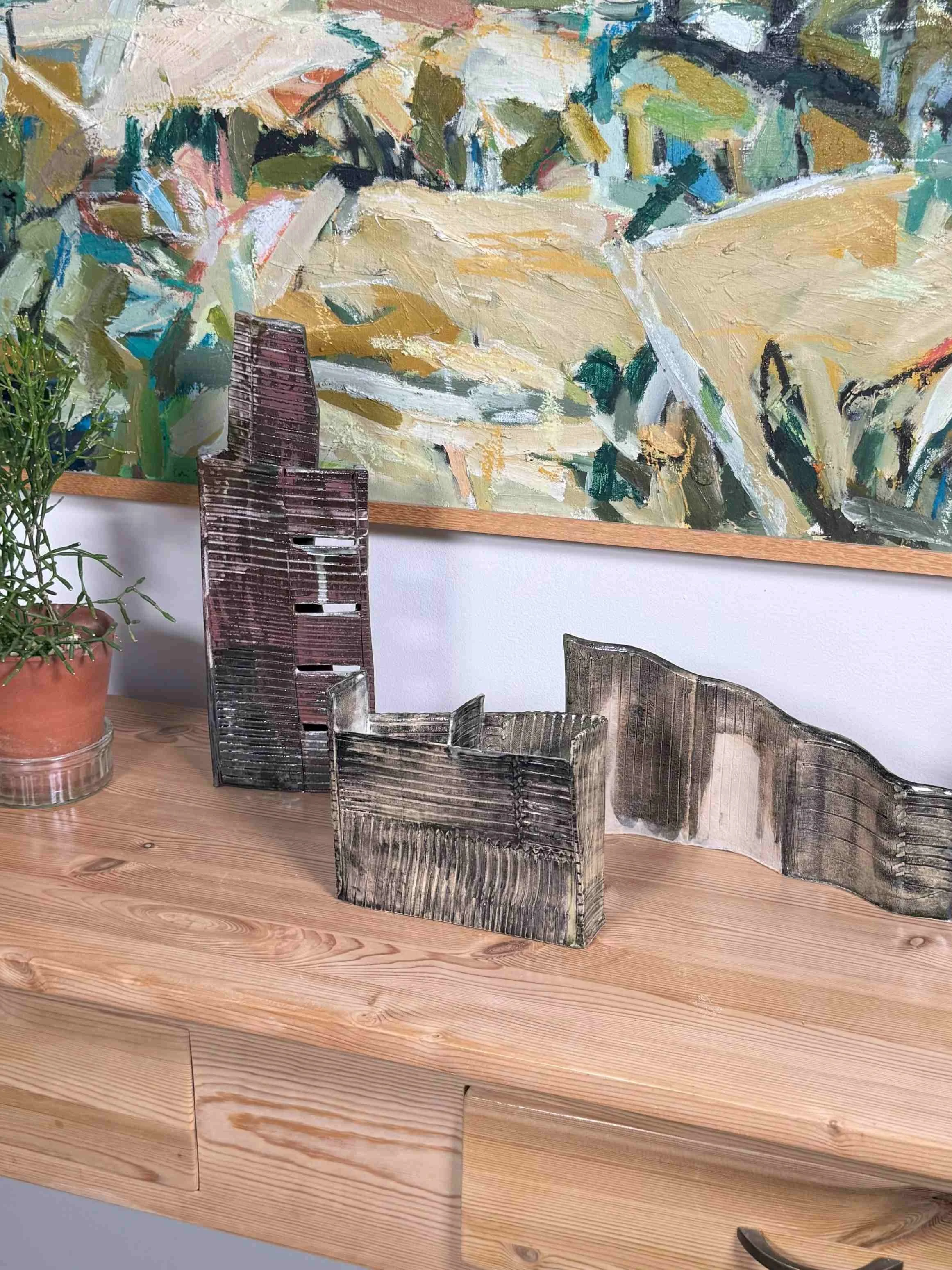 White stoneware sculpture Skyline 3 by ceramic Artist Cristina Lorenzet displayed with other sculptures on side table.
