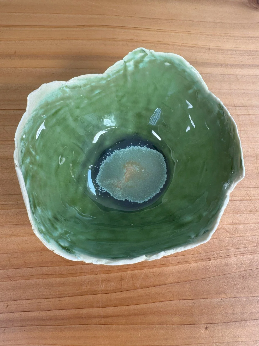 Top view of small rough-edged bowl by ceramic Artist Nupur Narain DeTar, hand-built, with green high-fired food-safe glaze.