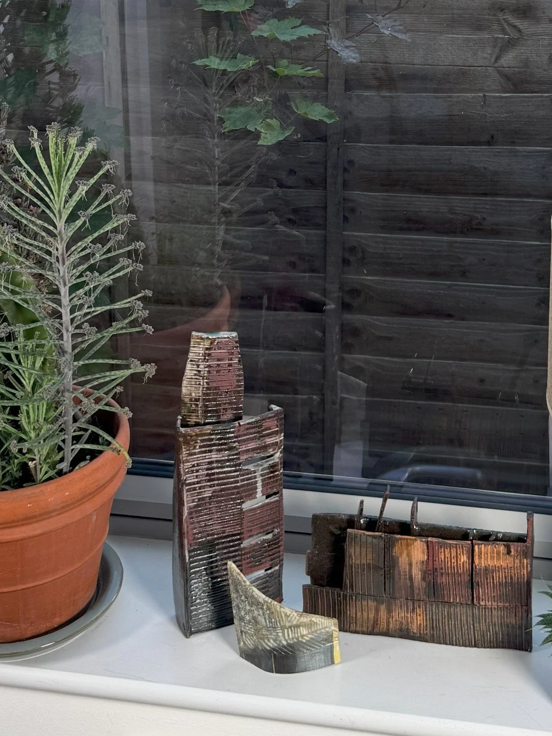 Fragment by ceramic Artist Cristina Lorenzet displayed on a windowsill with other sculptures from the same artist.