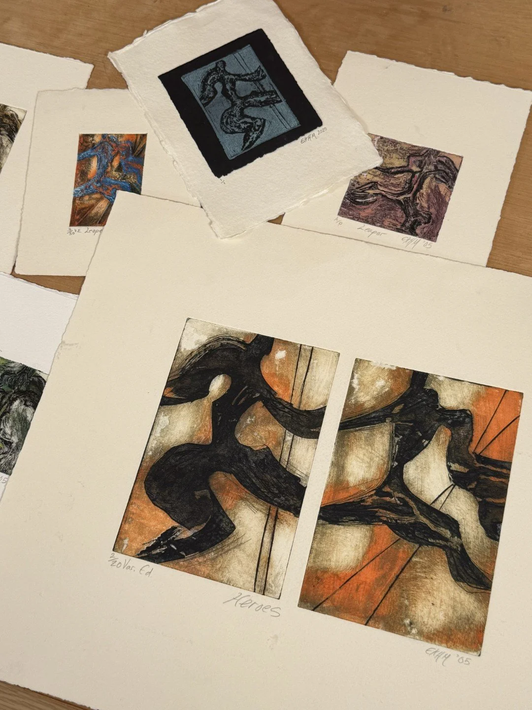 Heroes 2/20, a stunning collagraph and monoprint by Artist Noonie Minogue, arranged on a table with other prints.