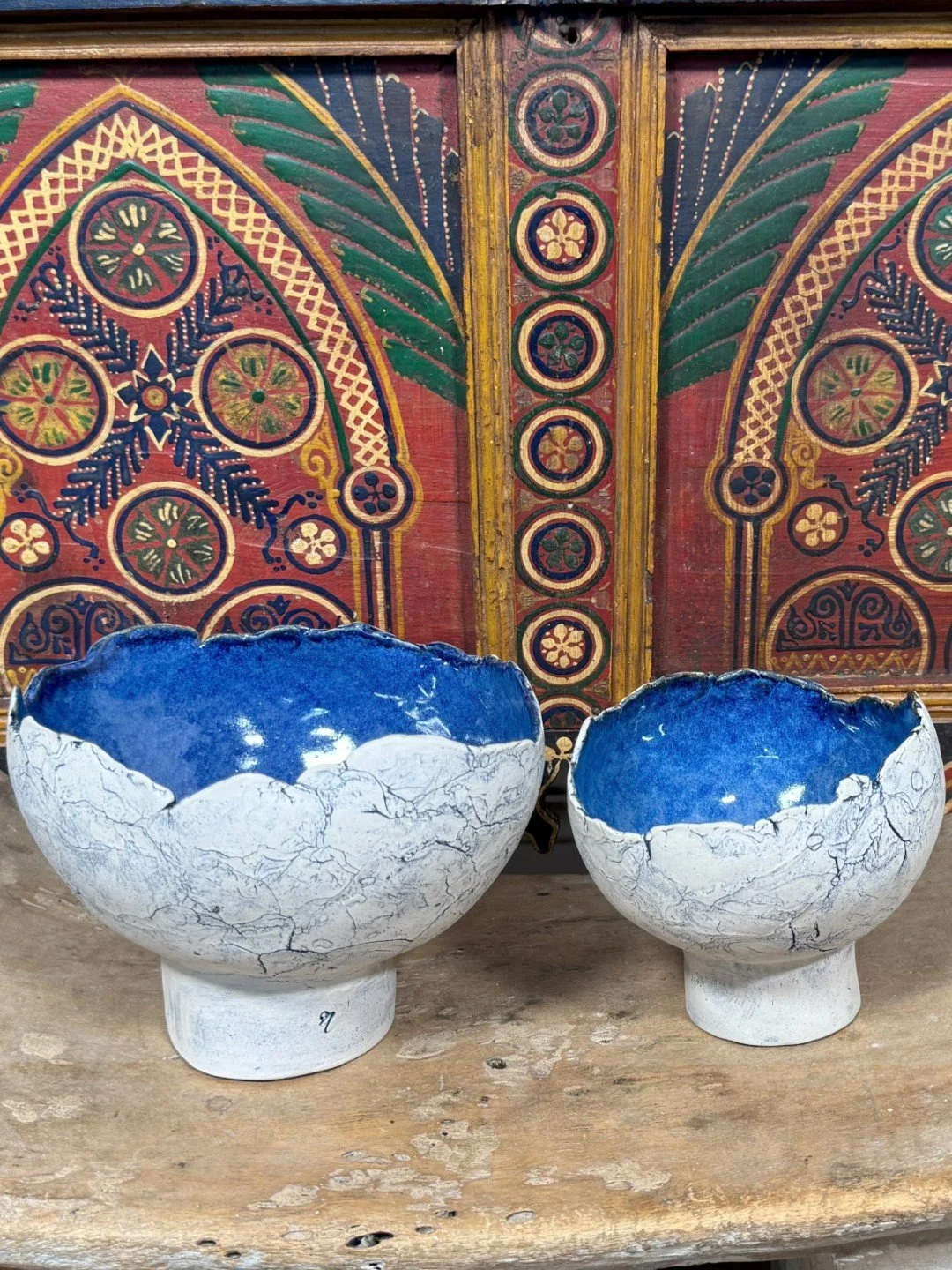 Medium crackle bowl with pedestal by Artist Nupur Narain DeTar, displayed with larger bowl in front of African cabinet.
