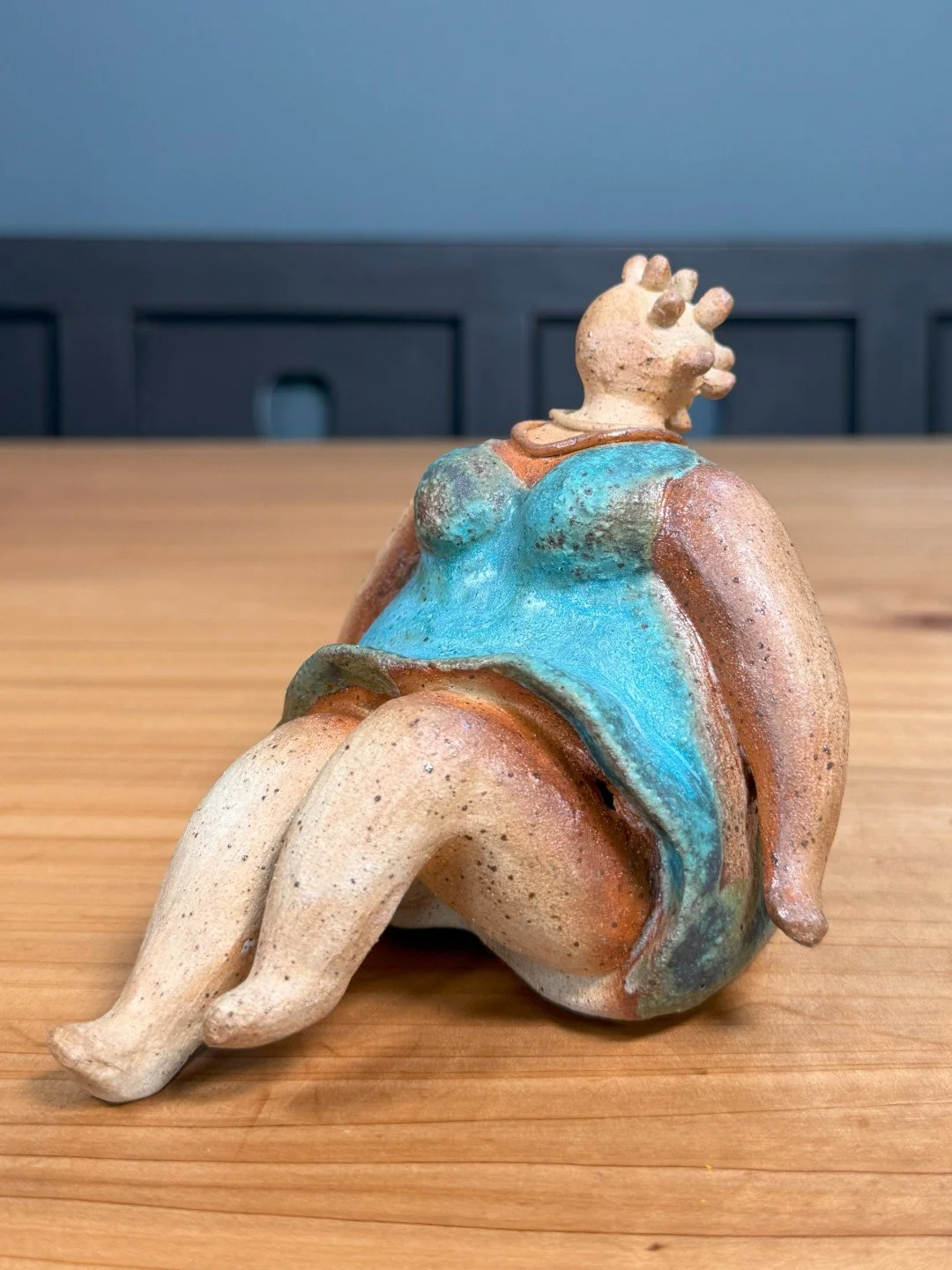 Angle view of Sitting lady in a dress by Artist Nupur Narain DeTar, a beautiful handmade ceramic sculpture.