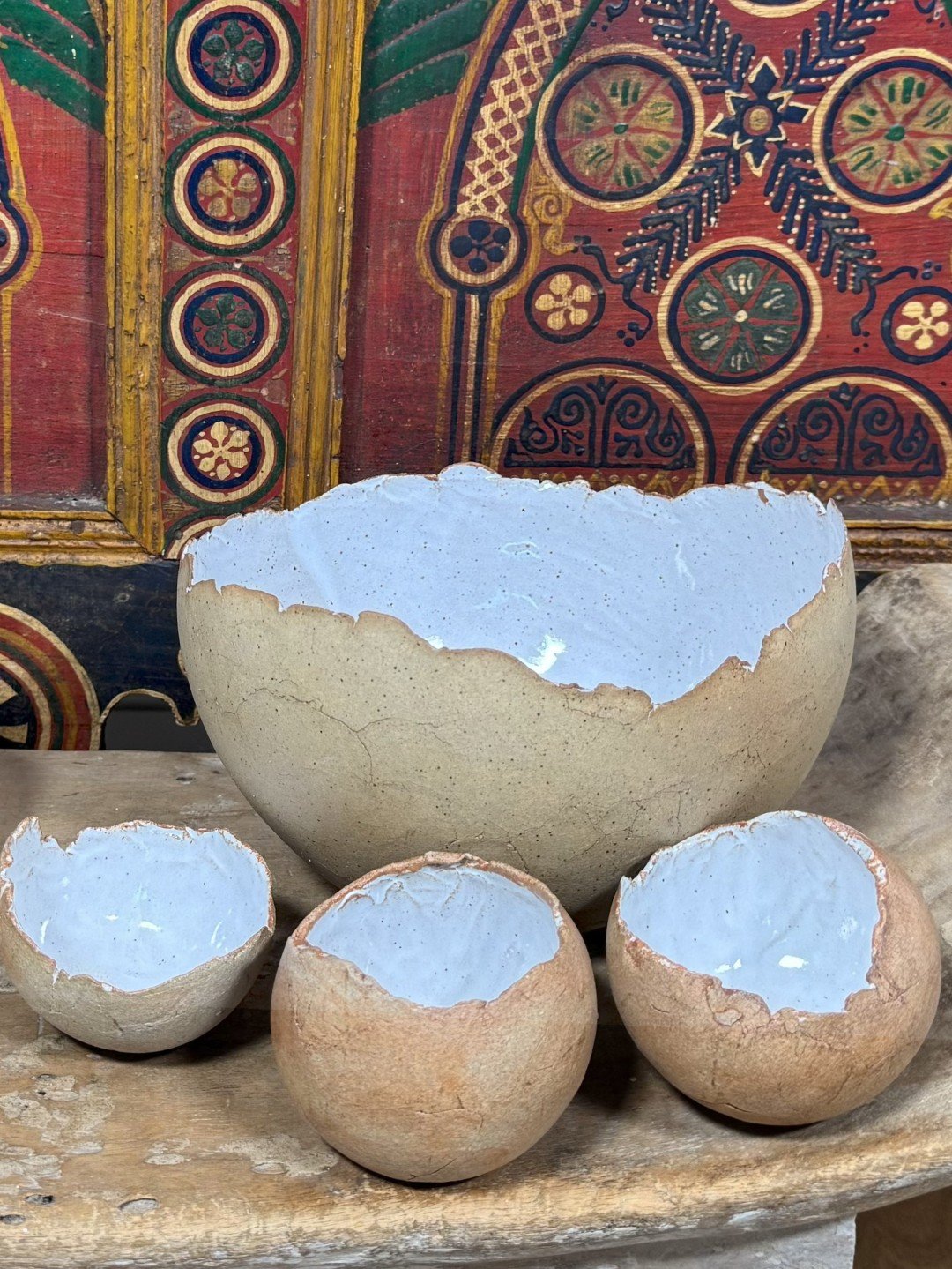 Beautiful hand-built crackle bowl by ceramic Artist Nupur Narain DeTar, displayed with smaller bowls on African furniture.