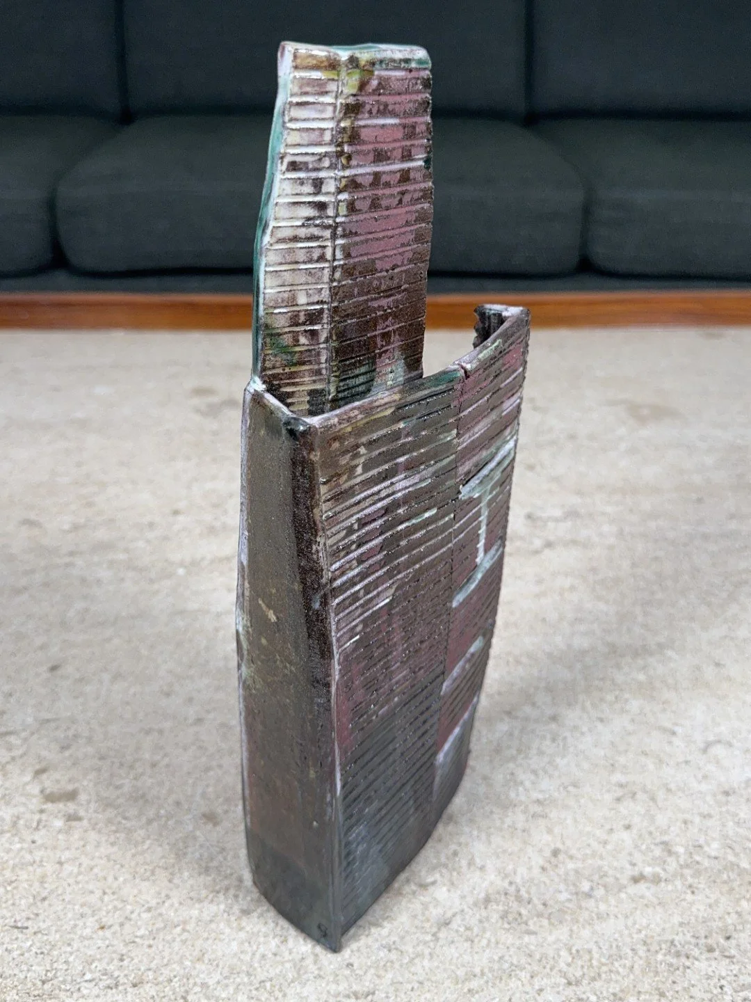 Angle view of Skyline 4 by ceramic Artist Cristina Lorenzet, a red stoneware sculpture decorated with white and green slips.