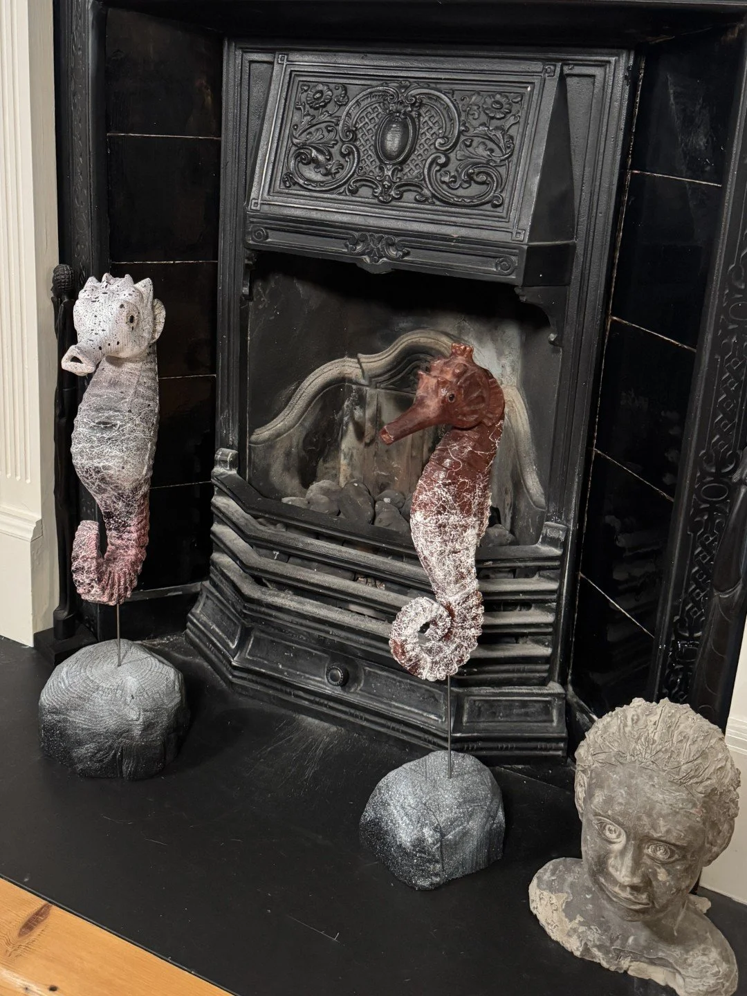 Seahorse sculpture by Artist Julien Hipeau, displayed alongside Skinny Seahorse in front of a dark fireplace in a house.