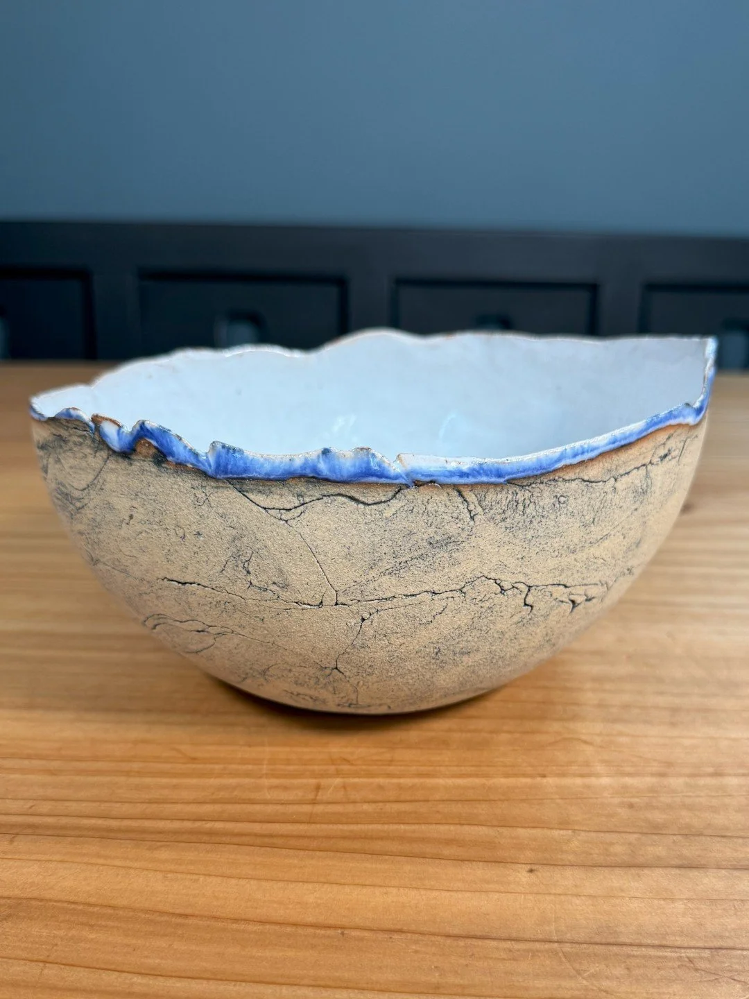 Large crackle bowl by ceramic Artist Nupur Narain DeTar, hand-built and high-fired bowl with blue rim and exposed exterior.