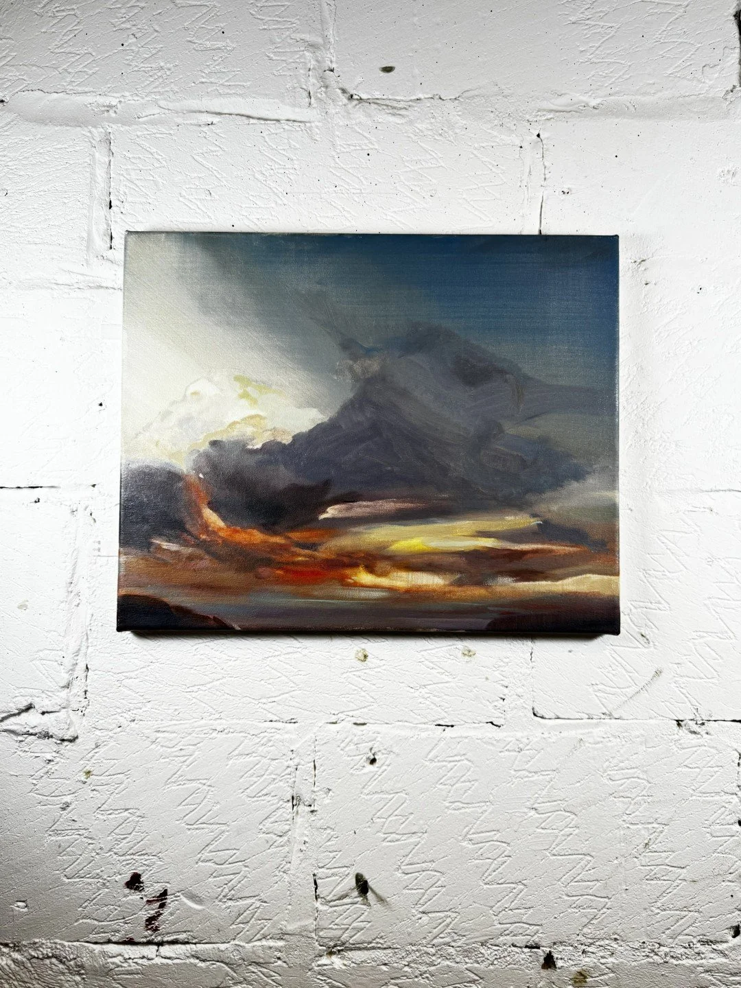 Original oil painting titled "Dusk" by Larissa, depicting dramatic sky over Cape Town, displayed on a white wall.