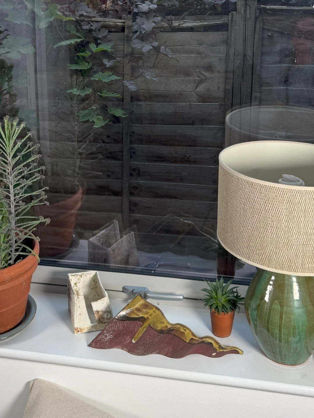 Rooftile fragment 1 by ceramic Artist Cristina Lorenzet displayed on a windowsill with other sculptures from the same artist.