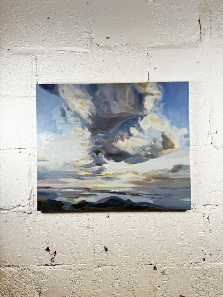 Oil painting of dramatic mid-summer blue skies and white clouds over Cape Town coast by Larissa Hollis, displayed on a wall.