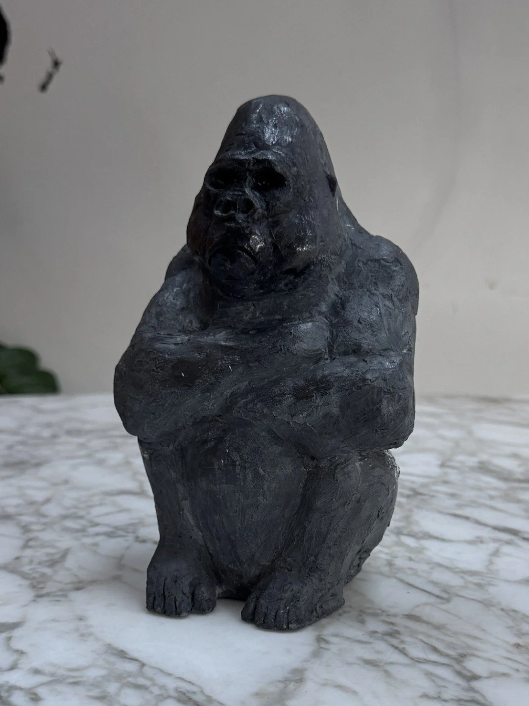 Seated Silverback sculpture by Artist Julien Hipeau, displayed on a marble table, cast in Jesmonite, as sustainable resin.