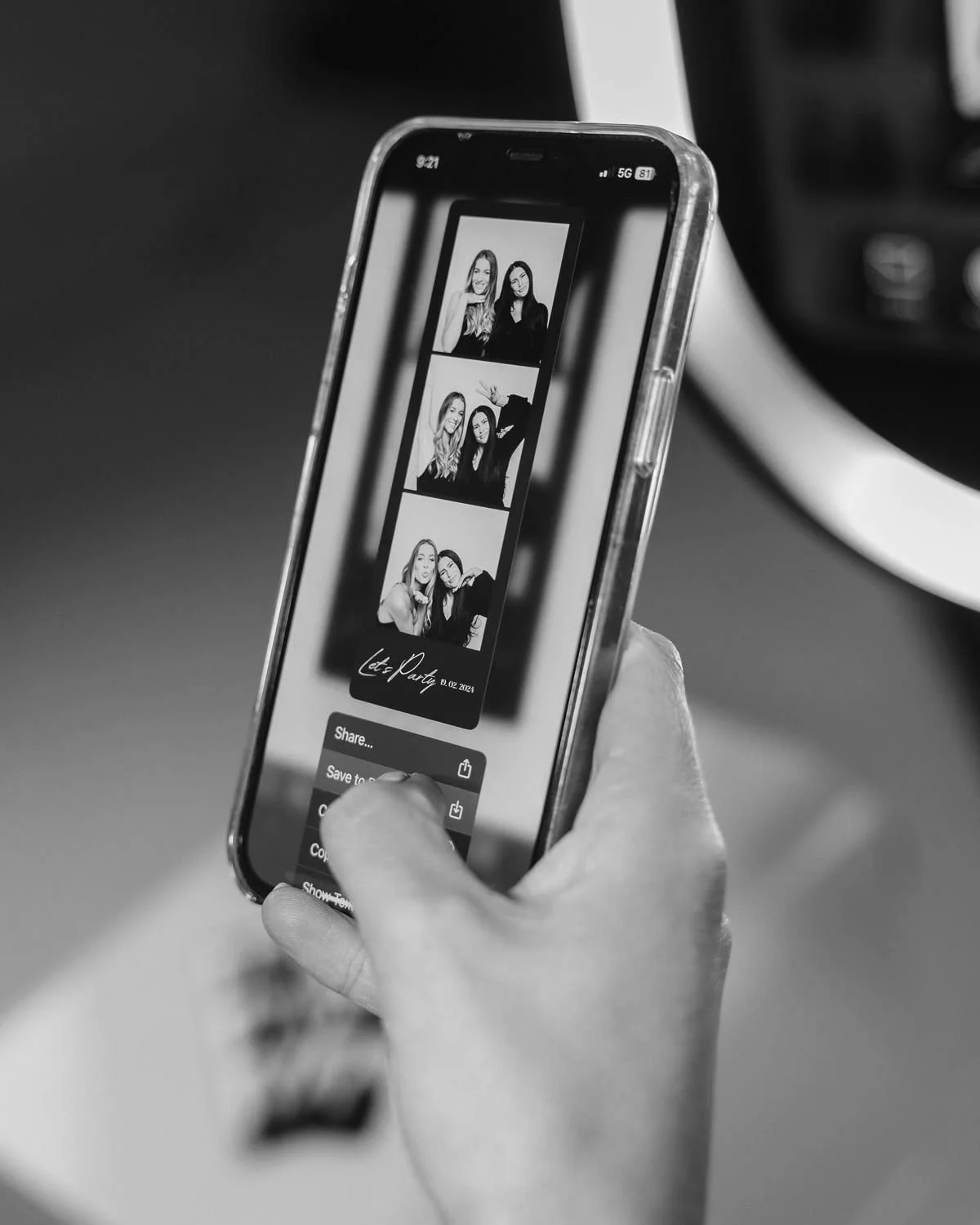 Osoba drzi smartphone a prohlizi si pasek z fotobudky se ctyrmi fotkami dvou zen, ktere delaji ruzne pozy.