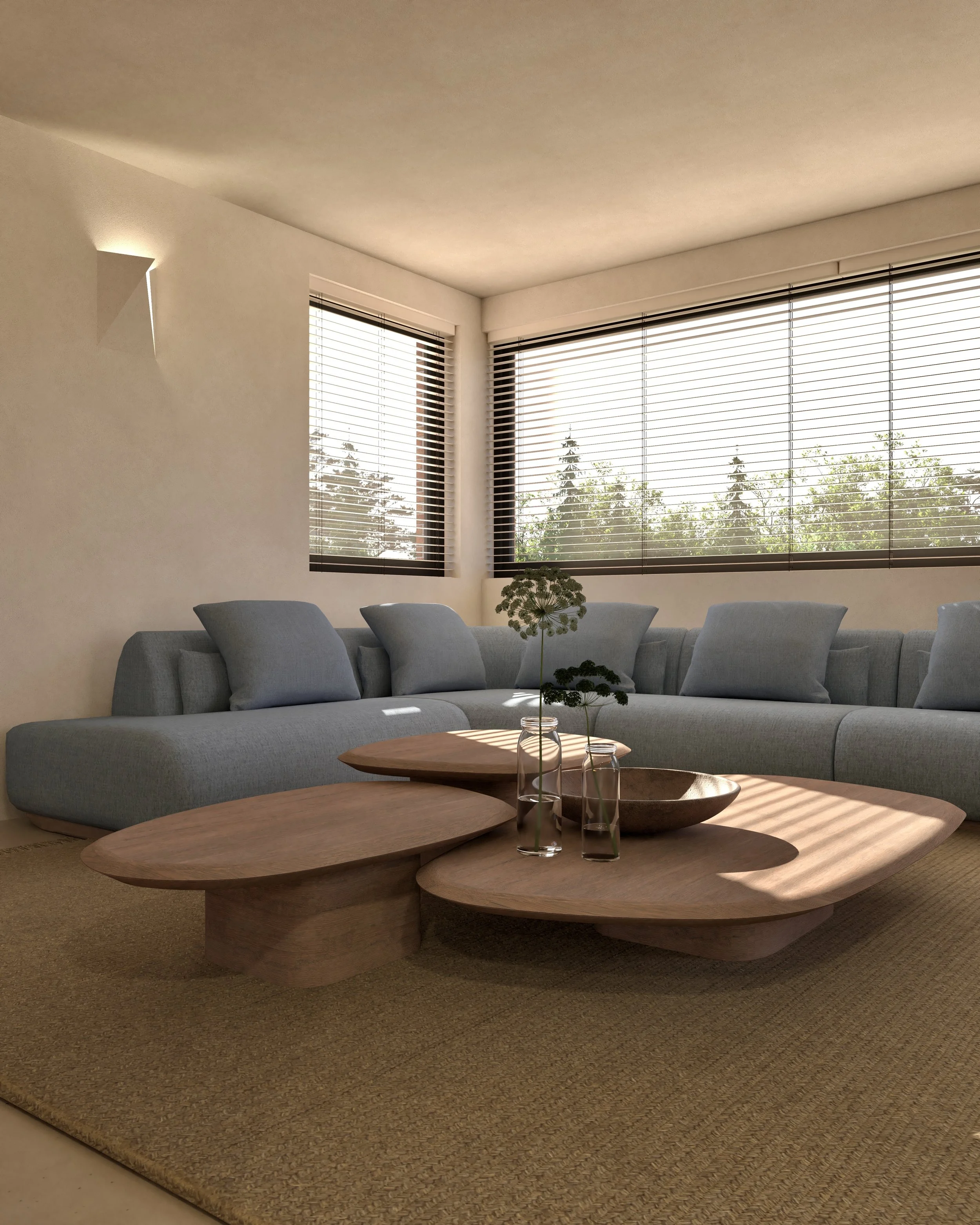 Een woonkamer met een grote blauwe bank, drie vazen met bloemen op een houten salontafel, grote ramen met uitzicht op bomen, en zachte verlichting.