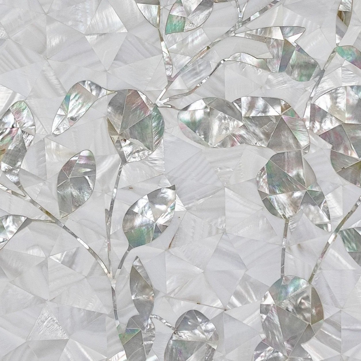 Close-up of a decorative surface with holographic, reflective leaves and abstract shapes.