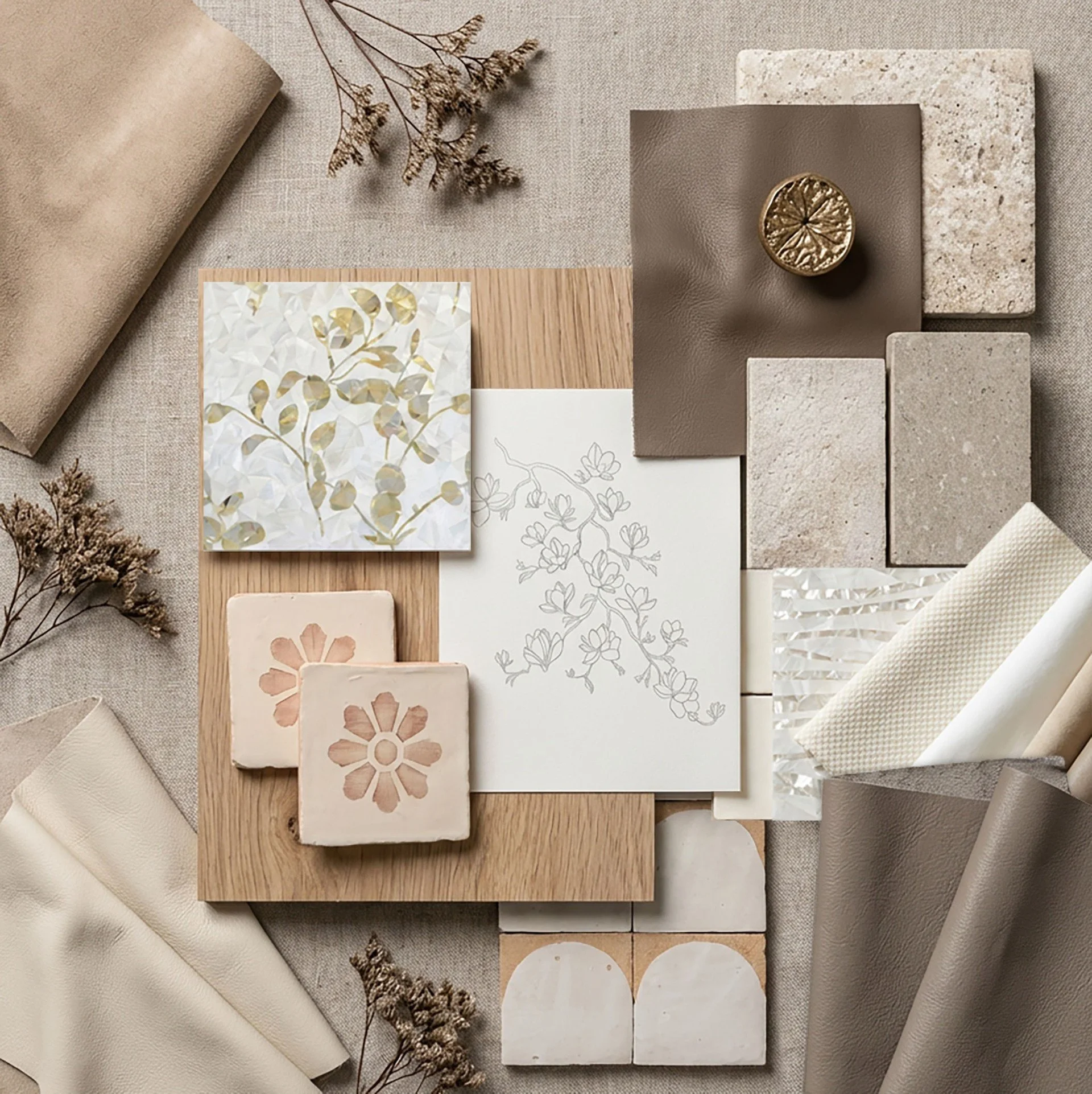 A collection of neutral-colored material samples, including tiles, fabrics, paper, and small decorative objects, arranged on a textured surface for interior design inspiration.