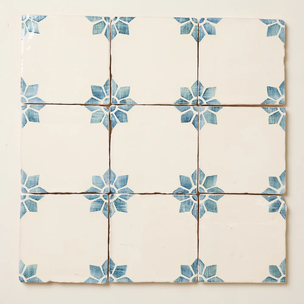 Nine ceramic tiles with a white background and blue floral pattern in the corners, arranged in a 3x3 grid.