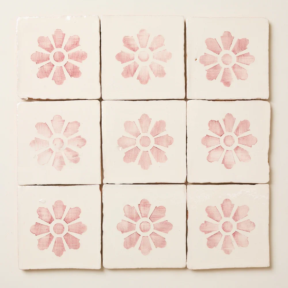 Nine white tiles with pink floral patterns arranged in a 3x3 grid on a wall.