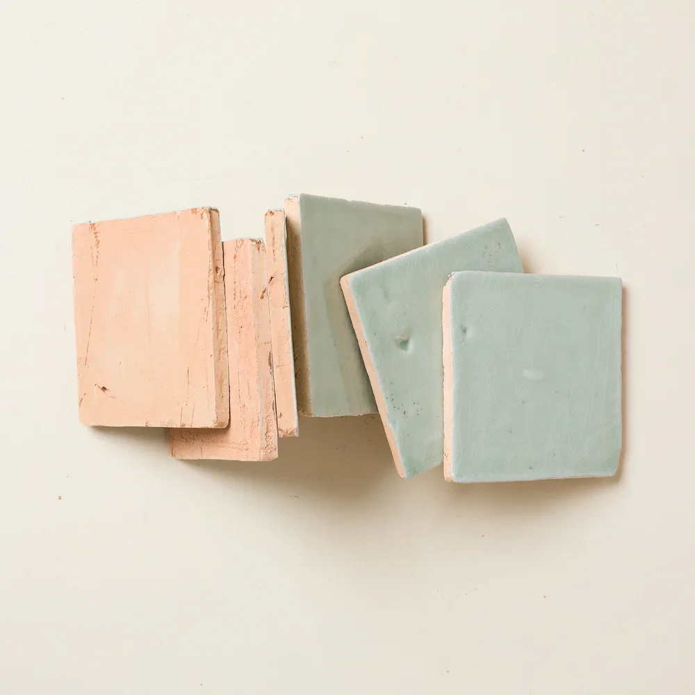 Set of pastel-colored square tiles in shades of pink, green, and blue arranged on a light surface.