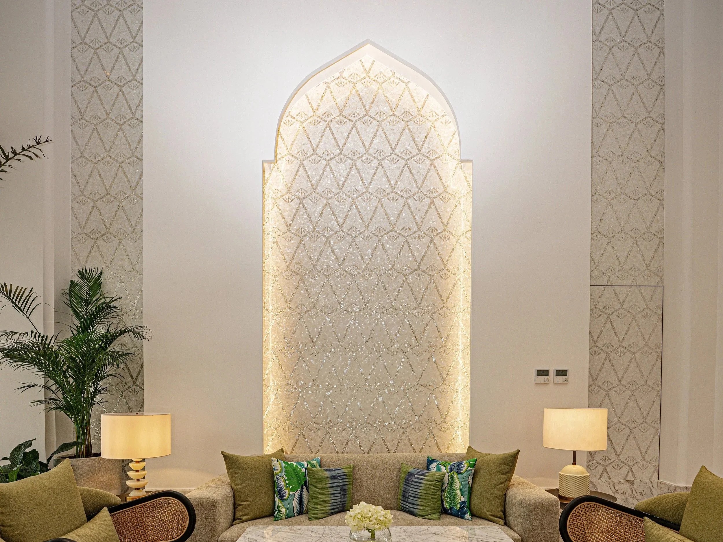 Elegant living room with a decorative wall feature, a sofa with colorful pillows, and two table lamps.