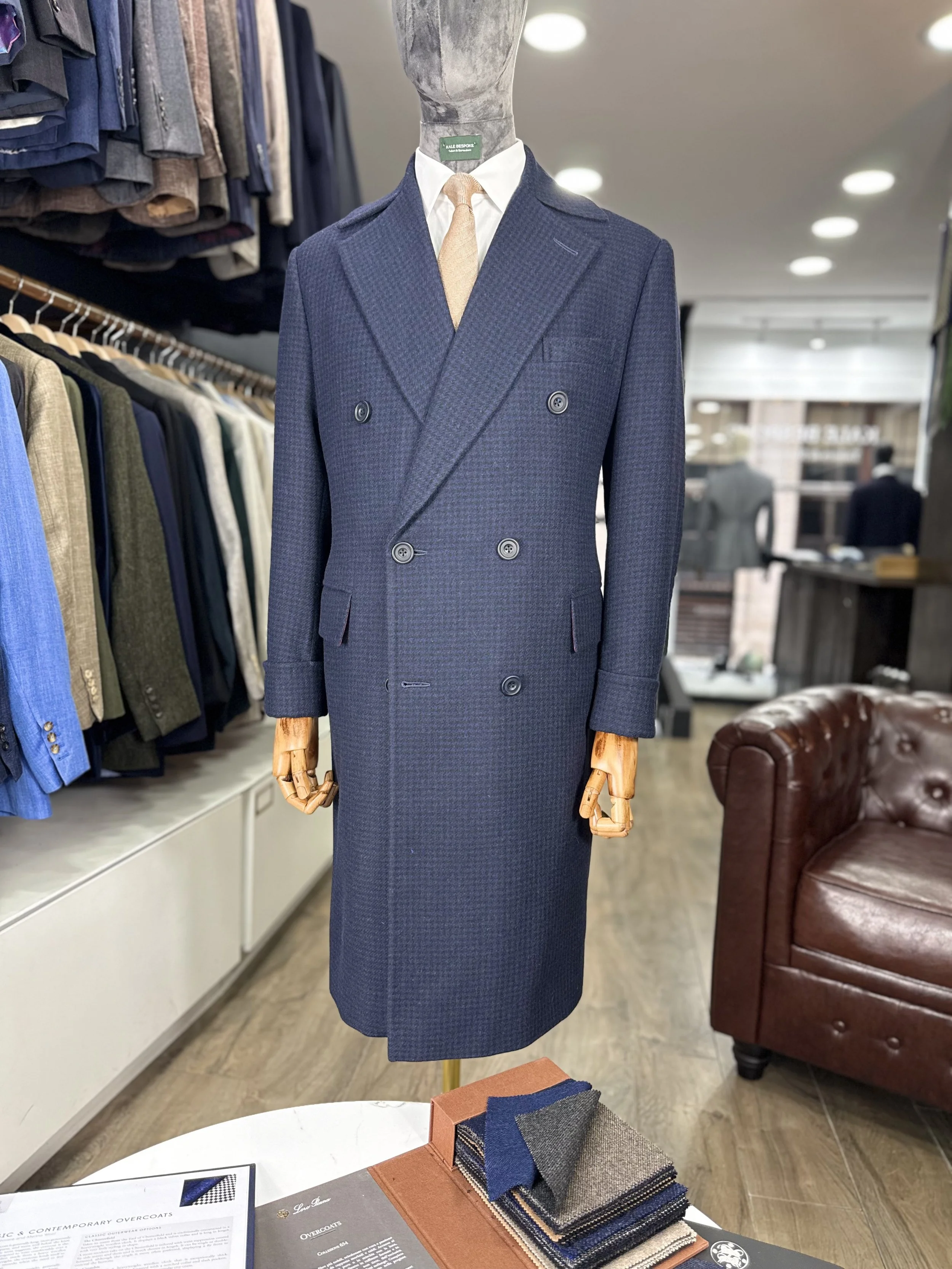 Mannequin dressed in a navy blue double-breasted suit with a light-colored tie and white shirt, displayed in a clothing store.