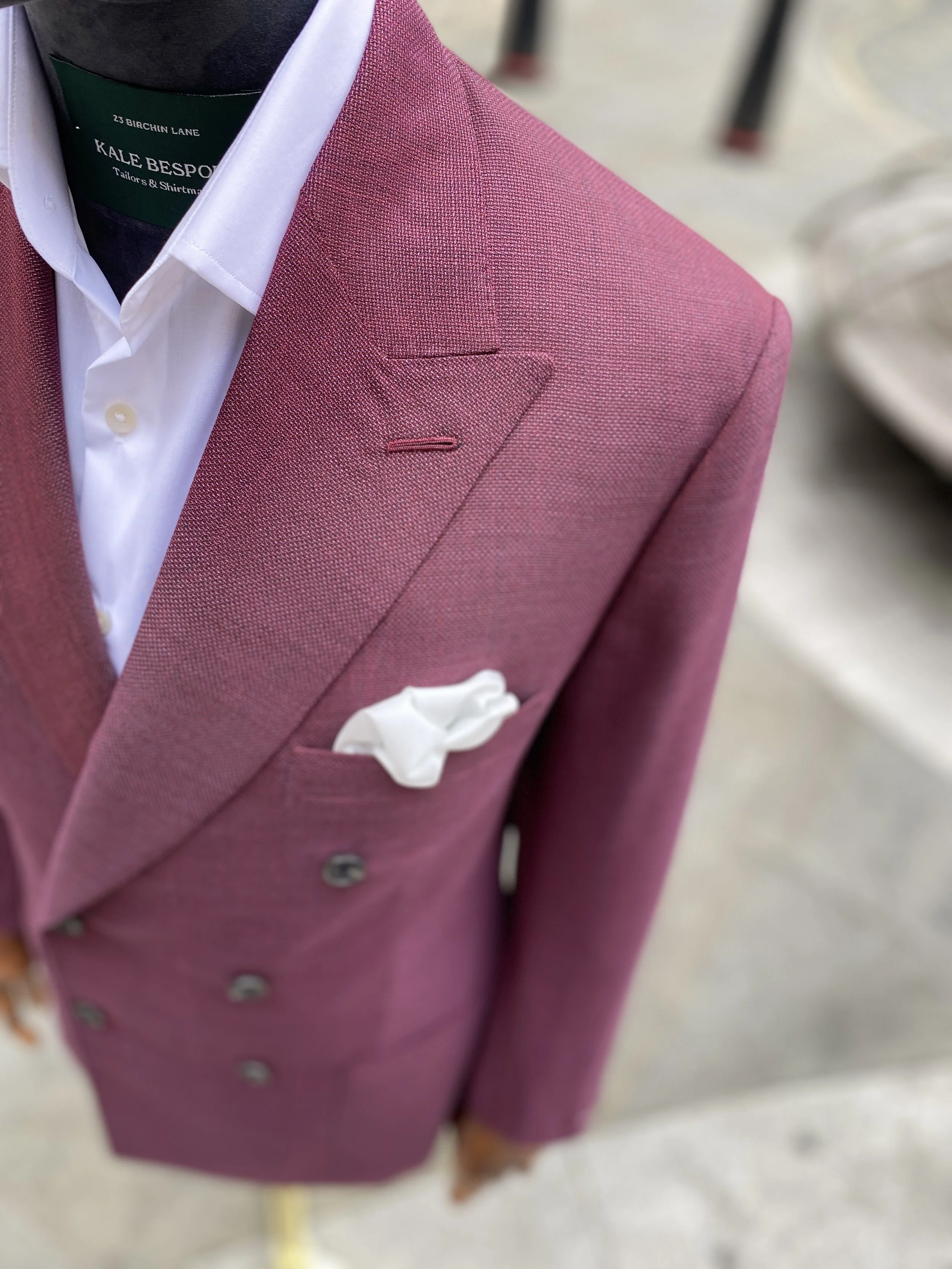 A striking, impeccably tailored men's bespoke blazer, crafted from a vibrant raspberry pink, Scabal, open weave fabric. This luxury statement jacket is constructed with a classic double breasted silhouette and features stylish patch pockets, represen