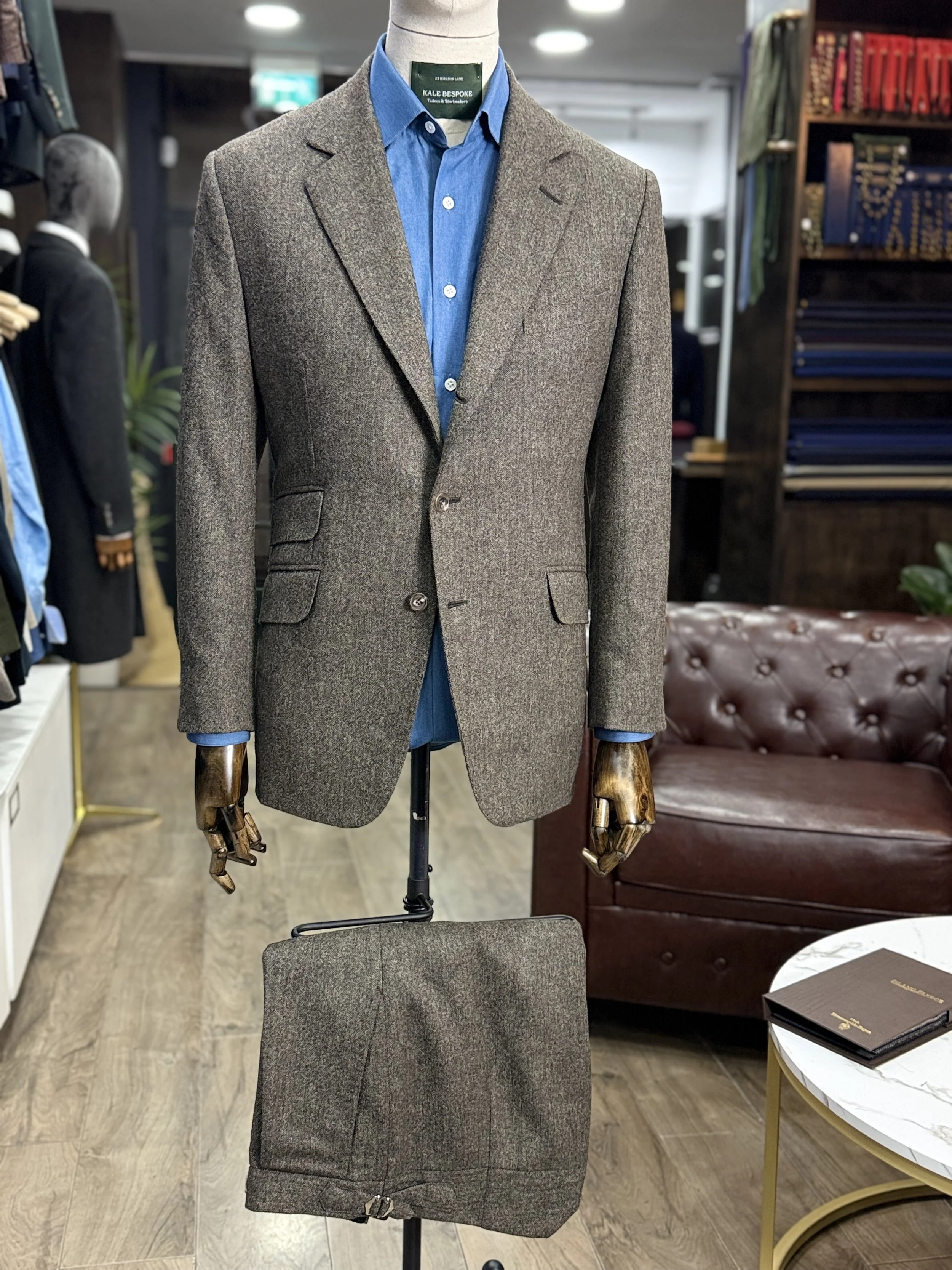 Brown mid-weight Donegal two-piece bespoke suit by Kale Bespoke Tailoring, handmade in London and showcased in our City of London showroom. Featuring a classic 3 roll 2 button jacket with slanted pockets and a ticket pocket, styled with a bespoke cha