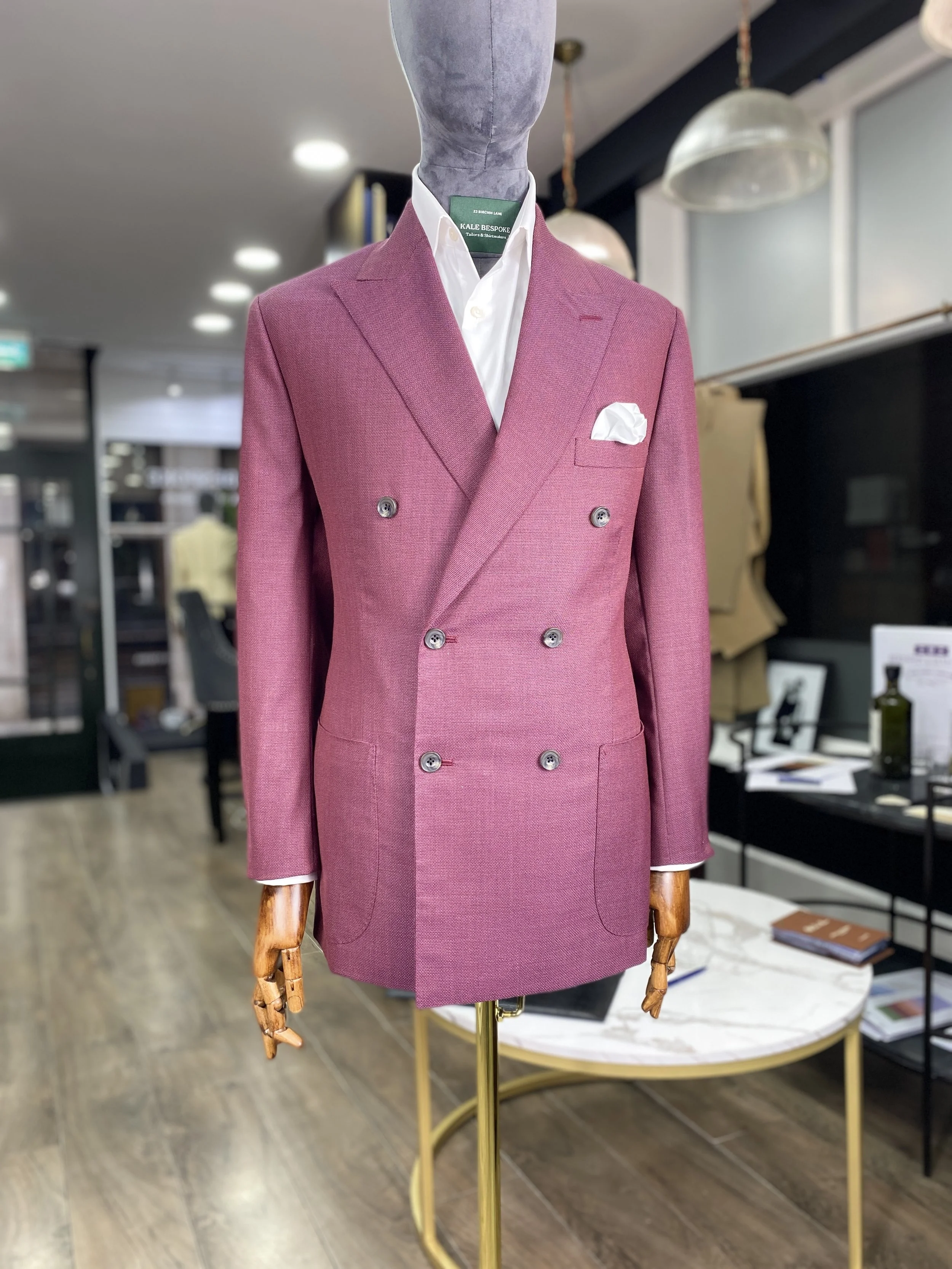 A striking, impeccably tailored men's bespoke blazer, crafted from a vibrant raspberry pink, Scabal, open weave fabric. This luxury statement jacket is constructed with a classic double breasted silhouette and features stylish patch pockets, represen