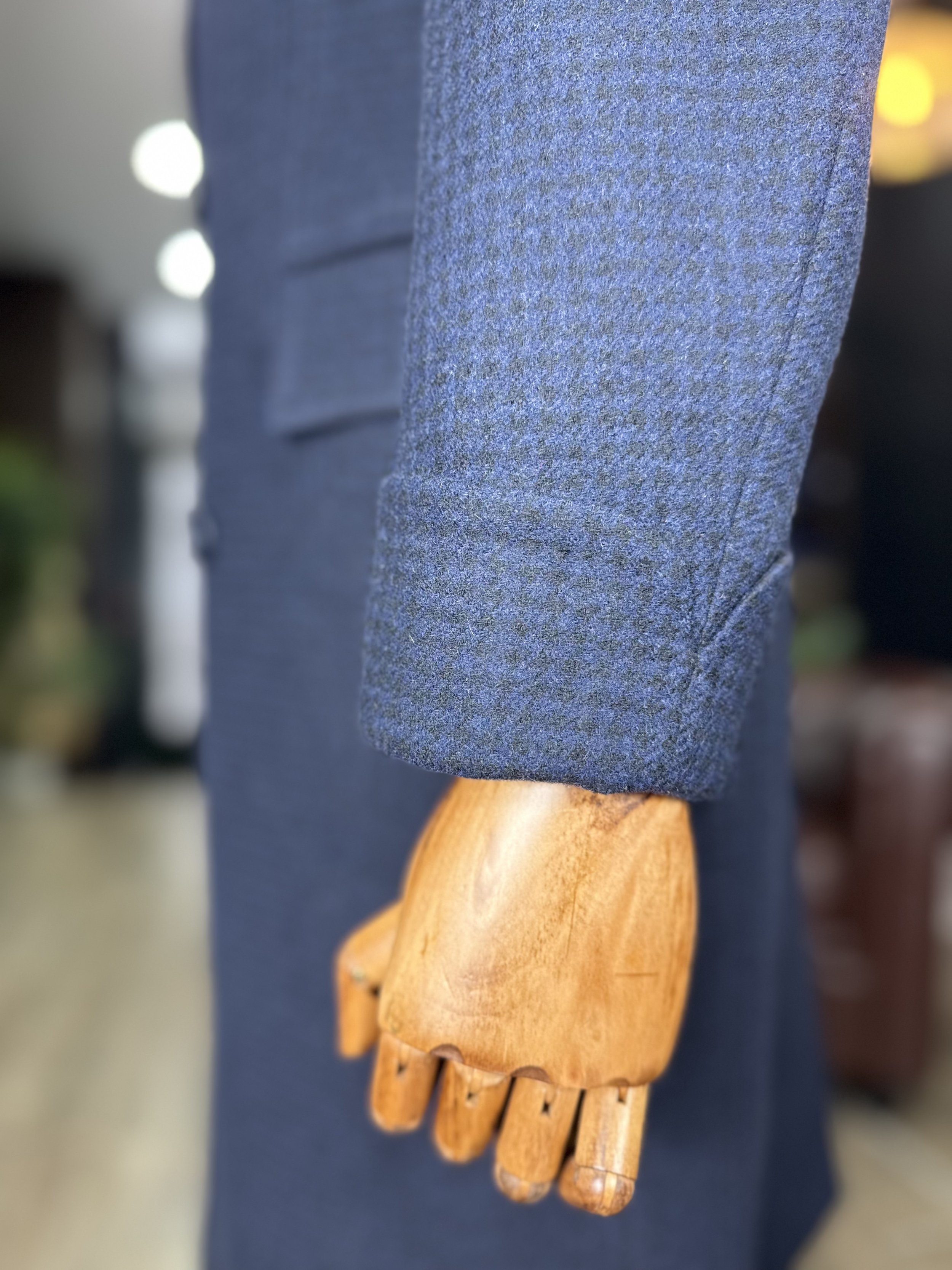Close-up of a wooden mannequin hand wearing a blue, textured fabric glove.