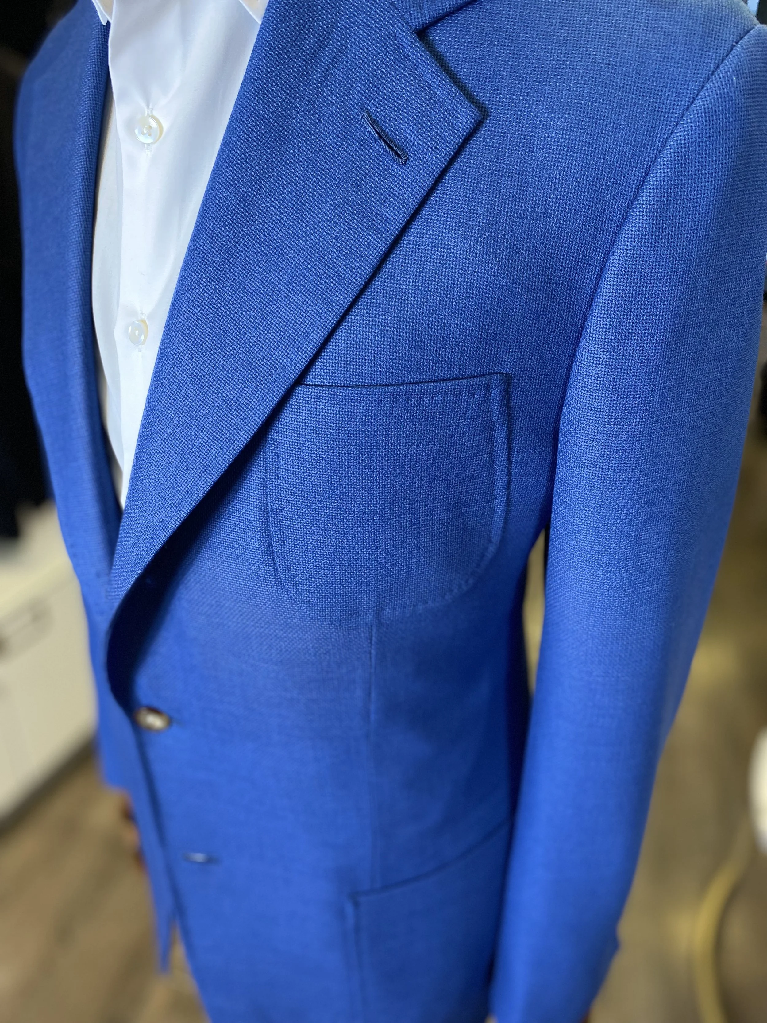 Crafted from luxurious Holland & Sherry mesh and hopsack basket-weave fabric, this sophisticated blue blazer combines timeless tailoring with effortless modern elegance. Designed with a classic notch lapel, patch pockets, and structured silhouette, i