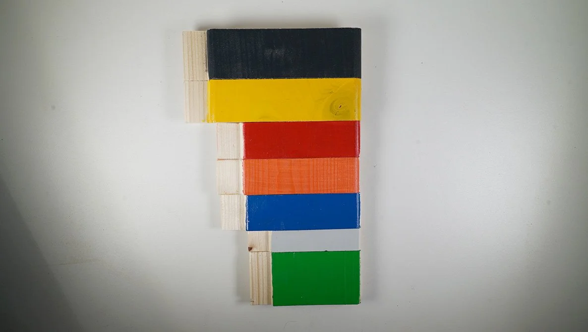 Mehrfarbige Spielwürfel in den Farben Schwarz, Gelb, Rot, Orange, Blau und Grün, auf einem weißen Hintergrund.