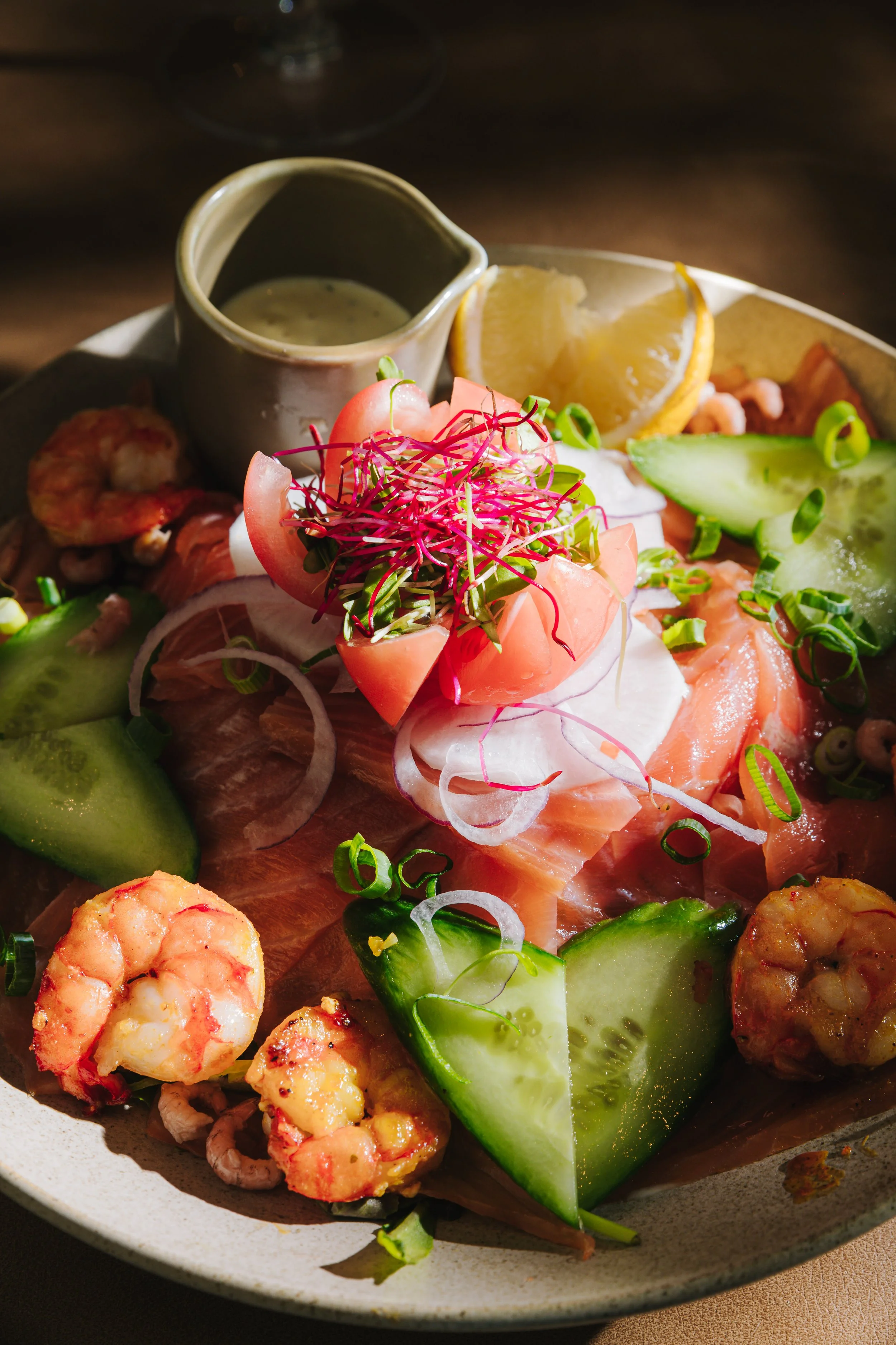 Een close up van een salade met tomaat, zalm en scampi.