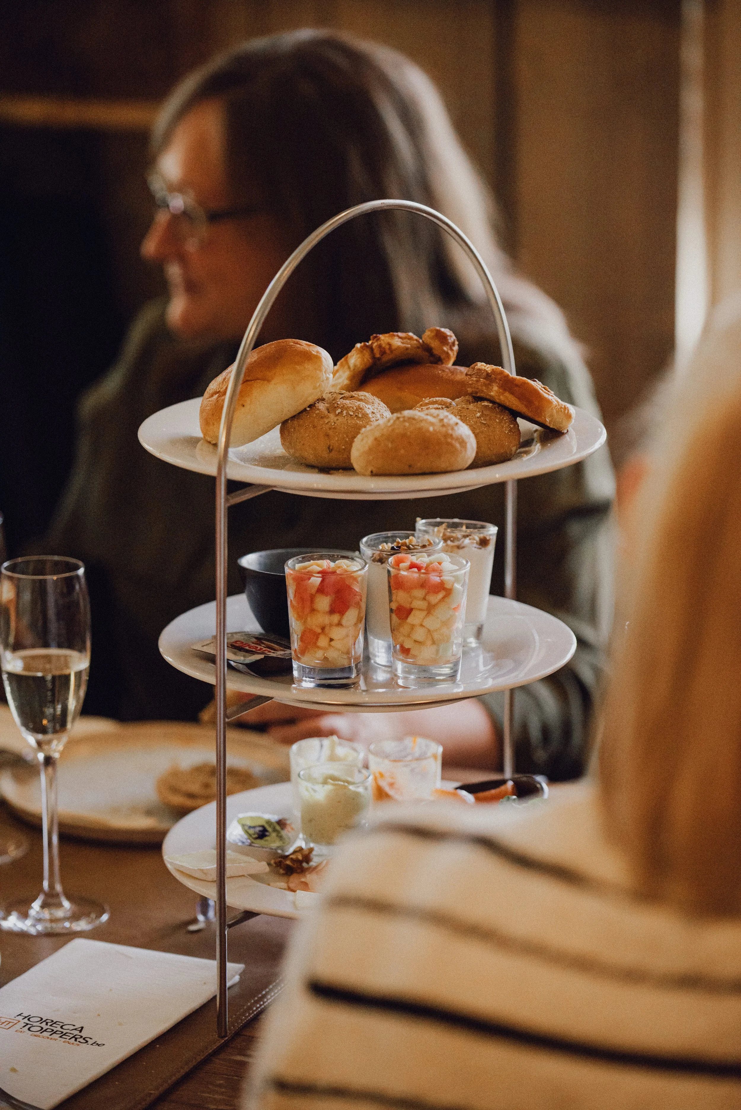 Een etagère met ontbijt (boterkoekjes, yoghurt, vers fruit, charcuterie, broodjes en meer) in een gezellige brasserie sfeer.