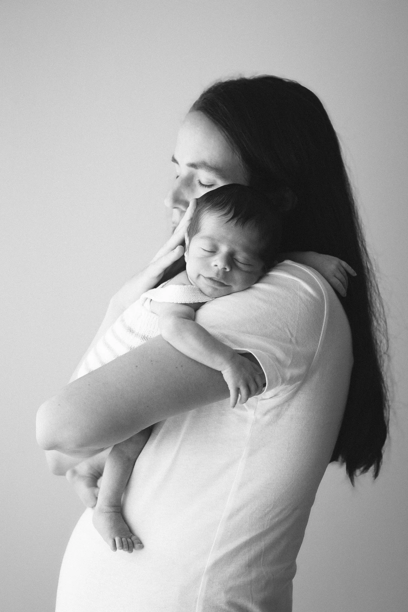 Una donna che tiene in braccio un neonato sorridente, in bianco e nero.