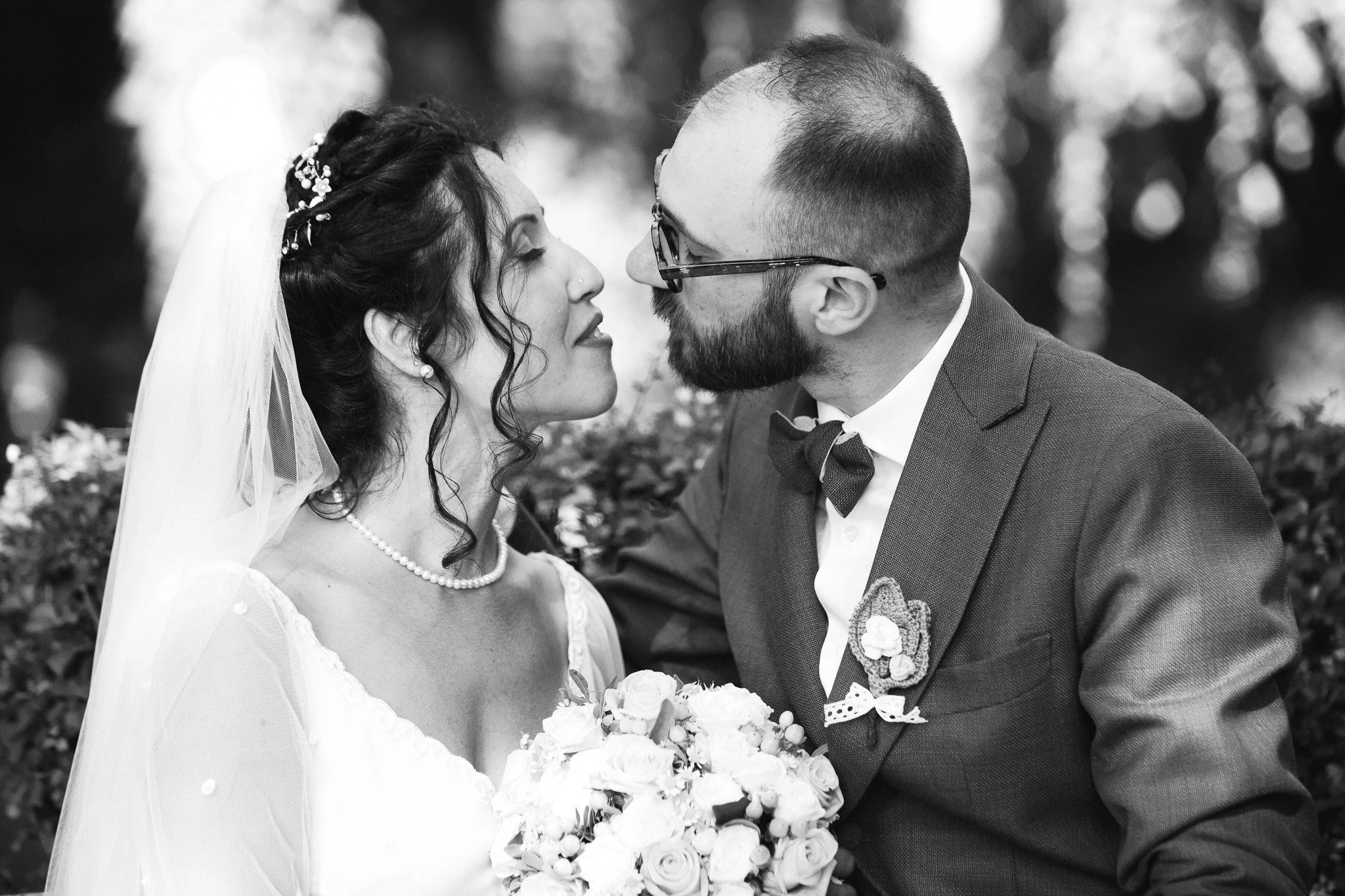 Coppia di sposi in un matrimonio, con la donna che sorride e il uomo che la guarda, in bianco e nero.