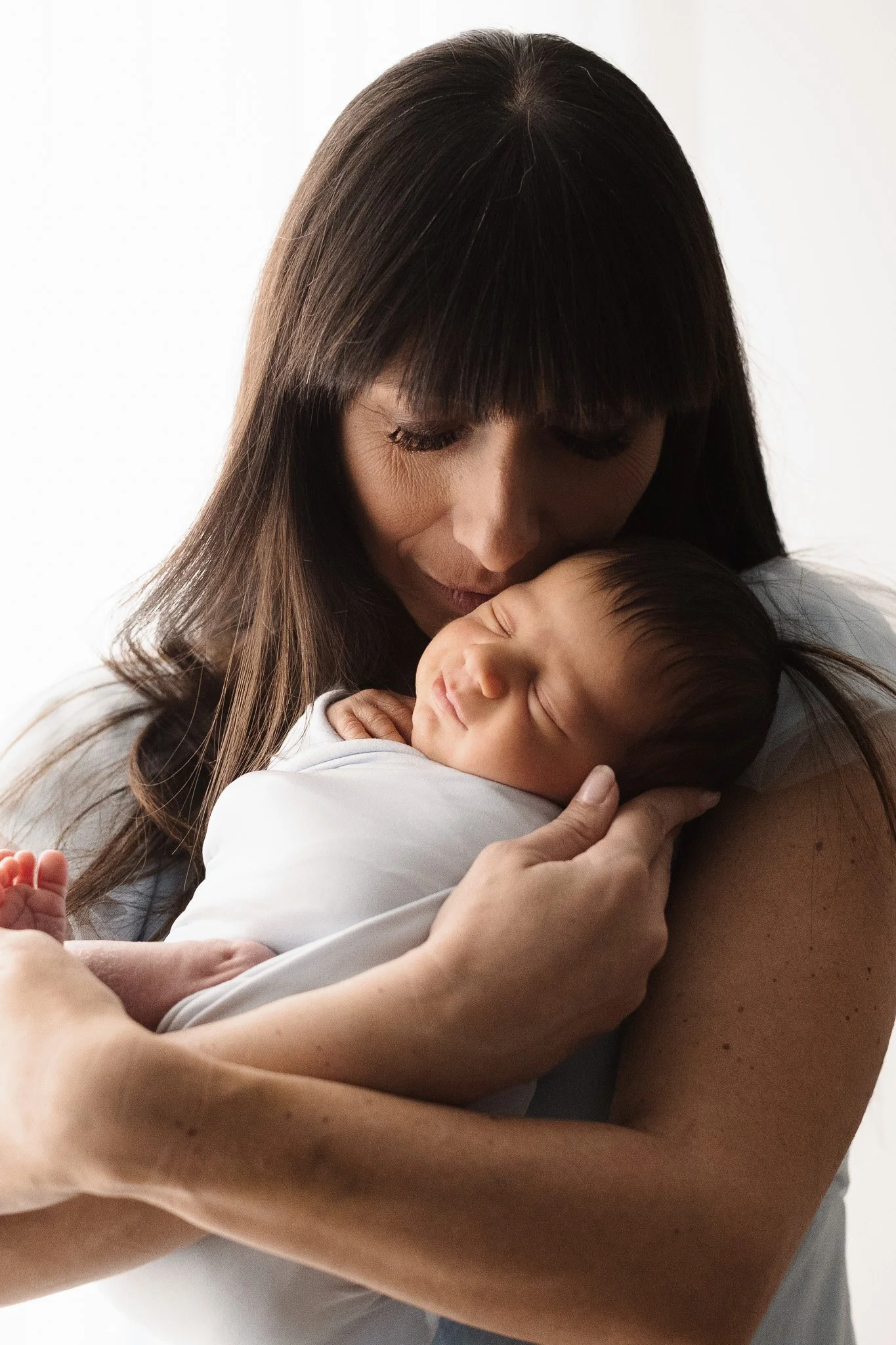 Una donna tiene un neonato avvolto in un abbraccio dolce e affettuoso.
