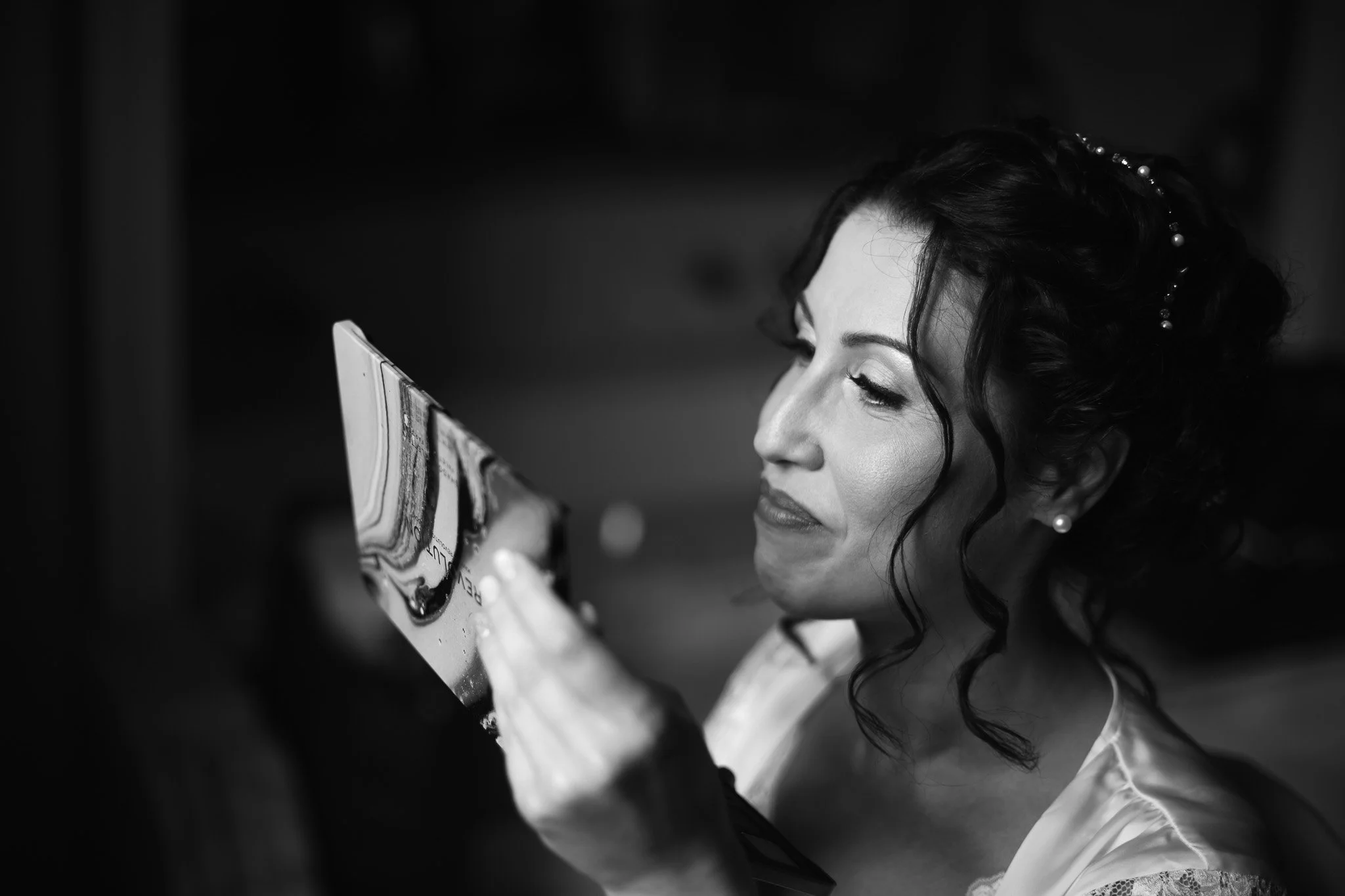 Ragazza con trucco elegante, acconciatura con onde e orecchini, che guarda un quadro in bianco e nero.
