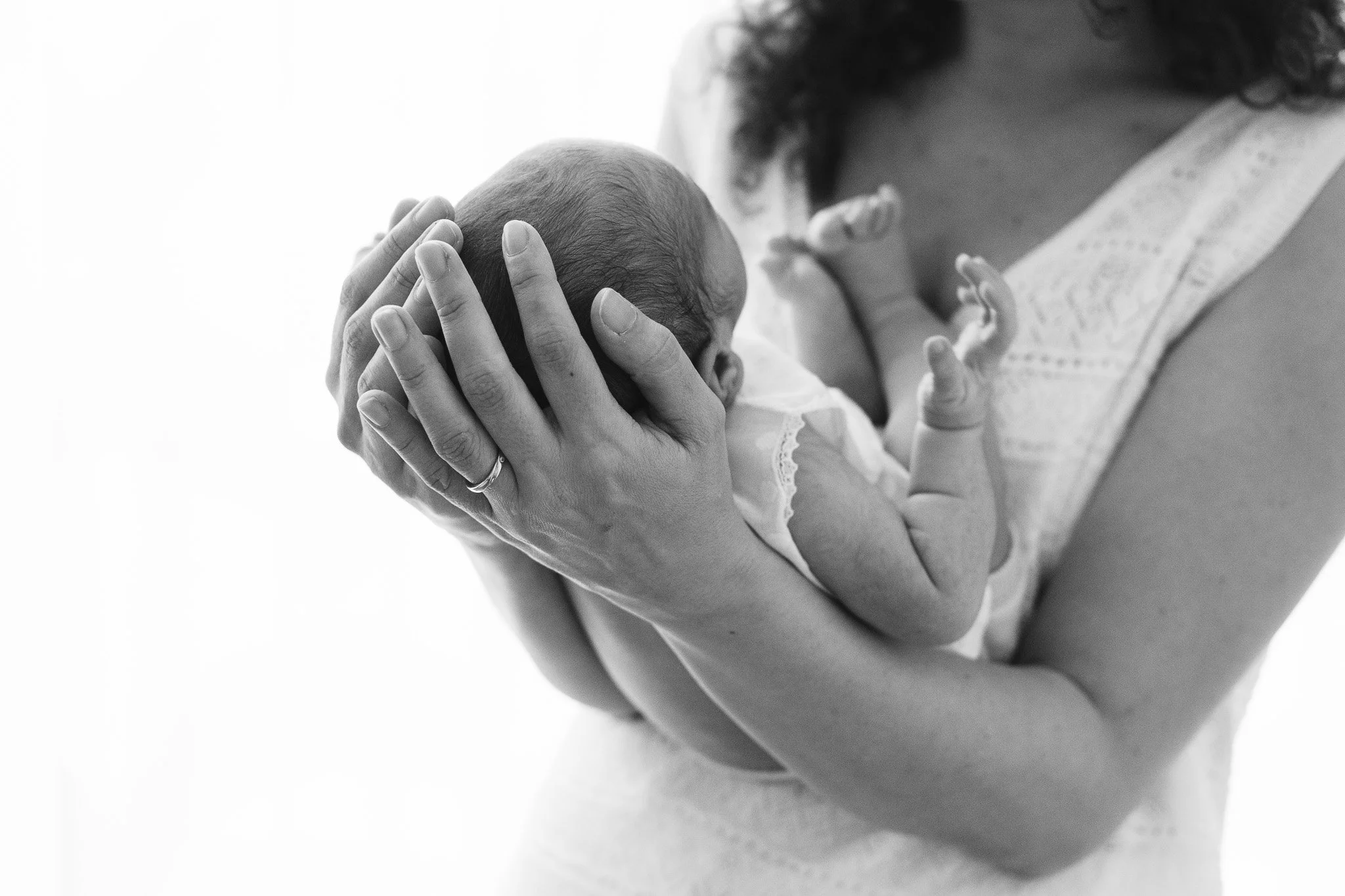 Una donna tiene un neonato in braccio, scattata in bianco e nero.