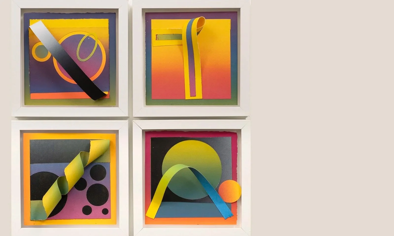Four colorful abstract art pieces in white frames, featuring geometric shapes, vibrant gradients, and mounted paper strips.