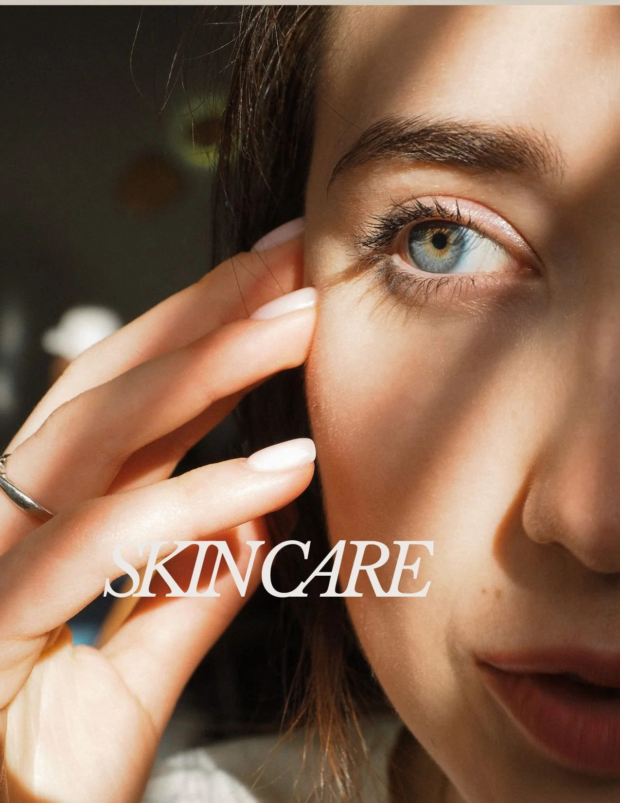 Close-up of a woman gently touching her cheek, emphasizing skincare, with the word 'SKINCARE' written across the image.