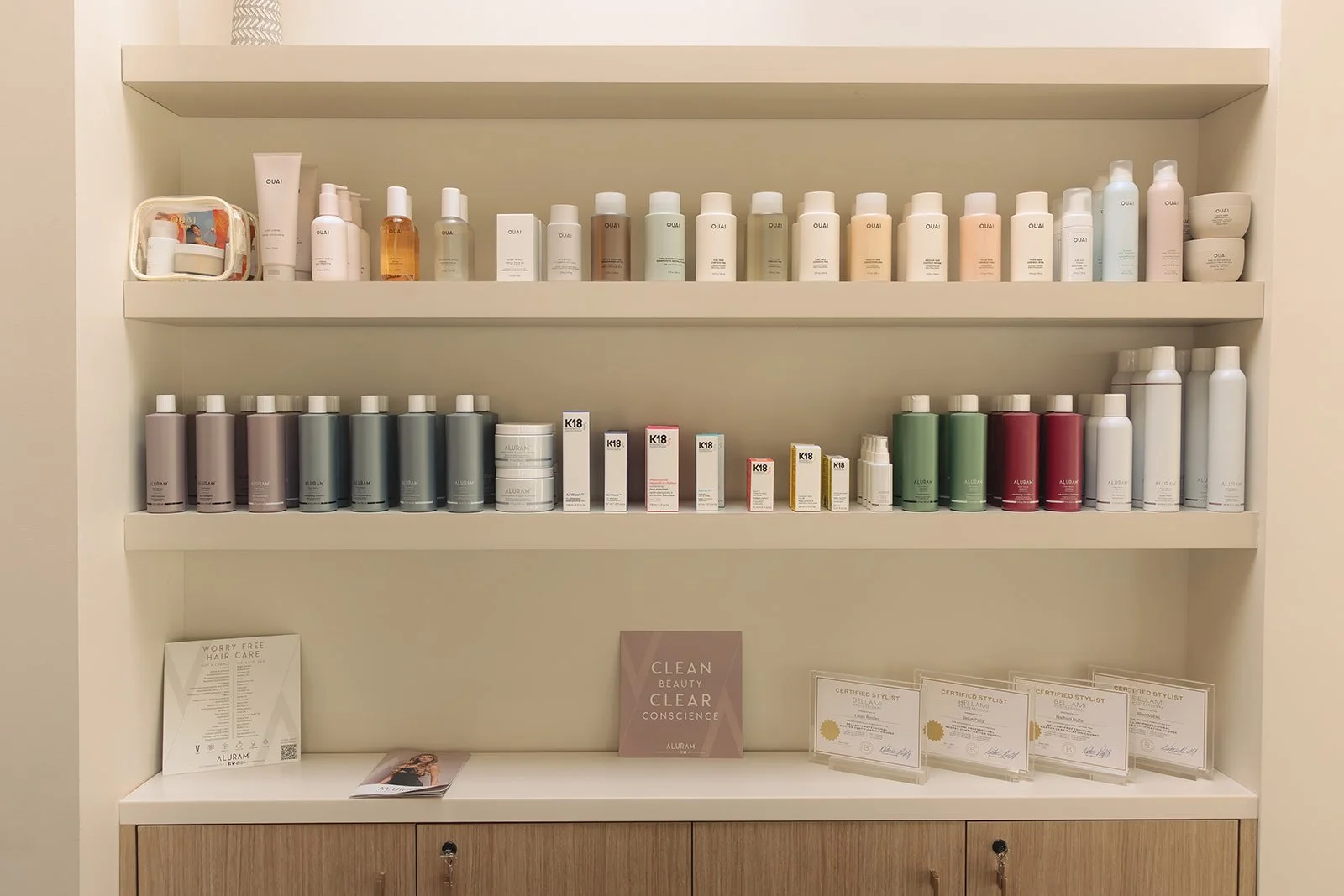 Display shelf with skincare and beauty products, certificates, and informational pamphlets in a salon or spa setting.