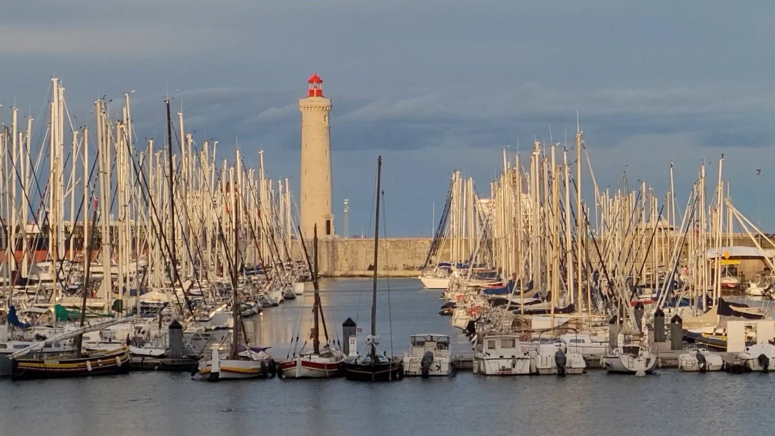 Saint-Louis lighthouse in Sète surrounded by sailboats at golden hour