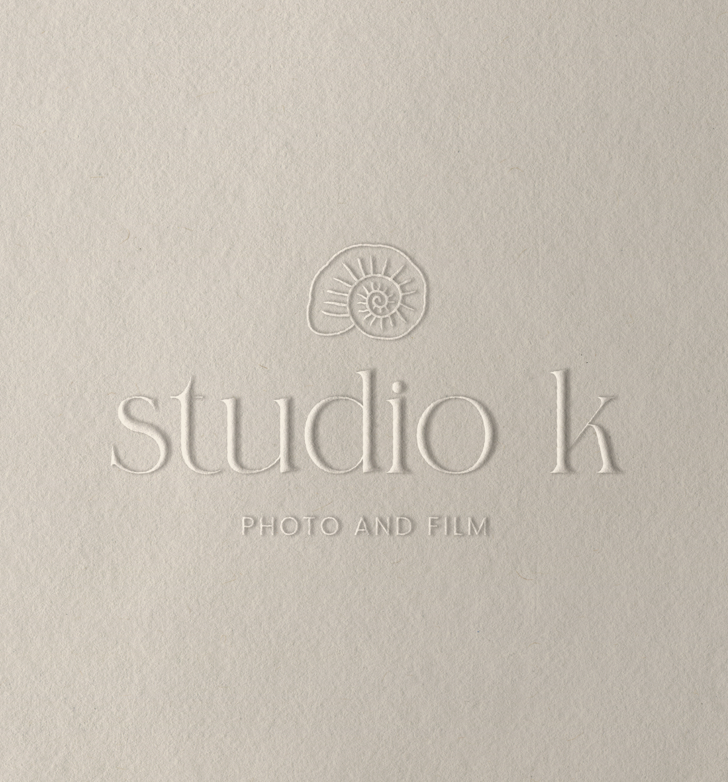 Embossed logo with a spiral shell icon above the text 'studio k' and the words 'PHOTO AND FILM' on a textured beige background.