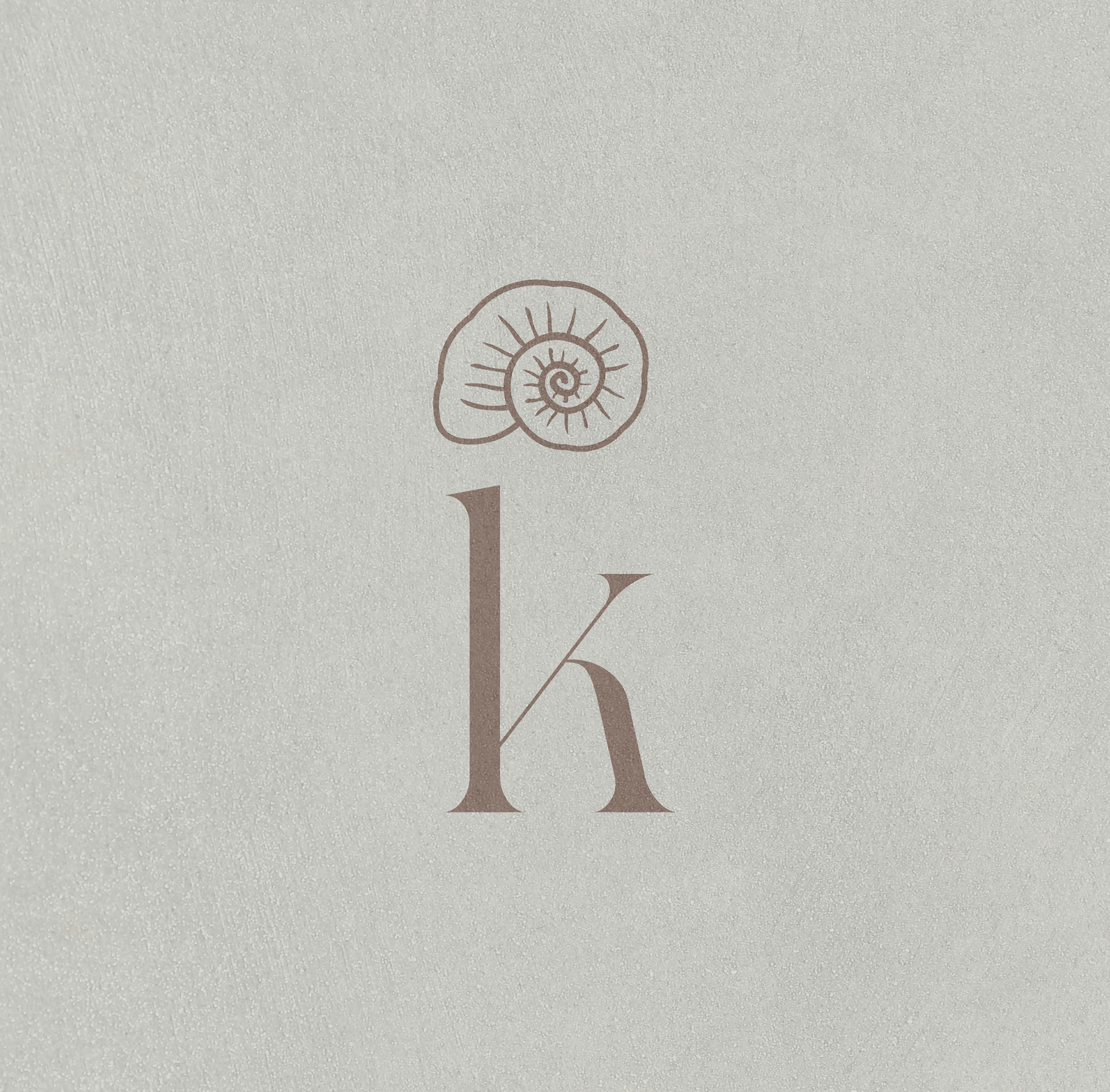 Minimalist logo with a large lowercase letter 'k' and a stylized ammonite shell above it on a textured light background.