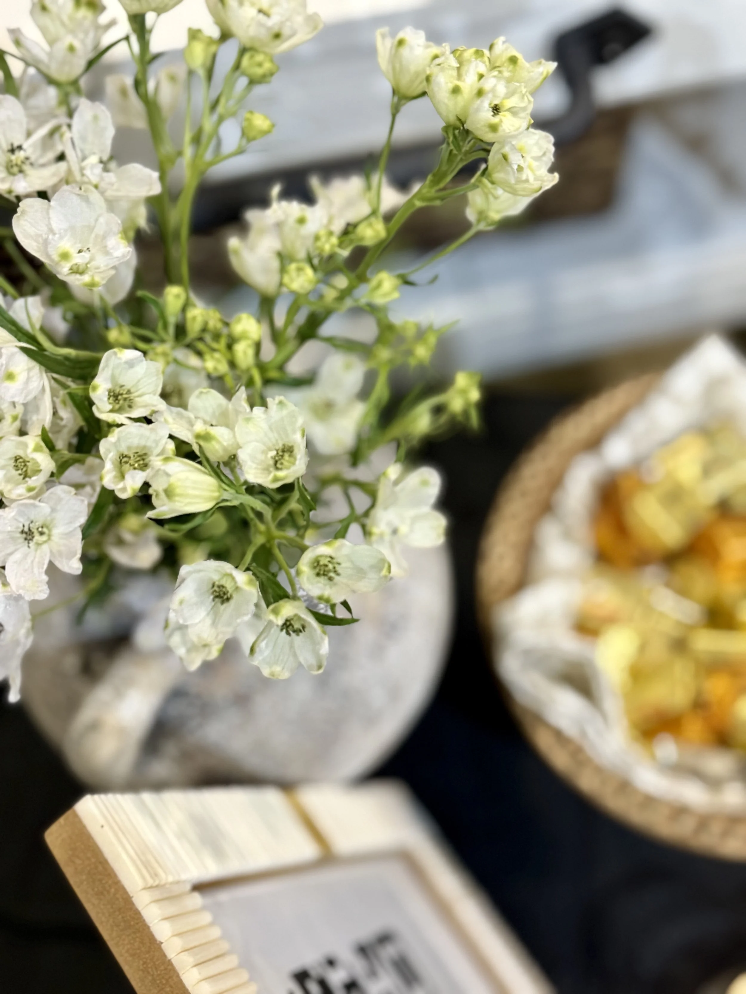 Close-up of a flower cart arrangement with white flowers in a stone pot. Our stylish displays elevate your event with the effortless elegance of fresh, local flowers.