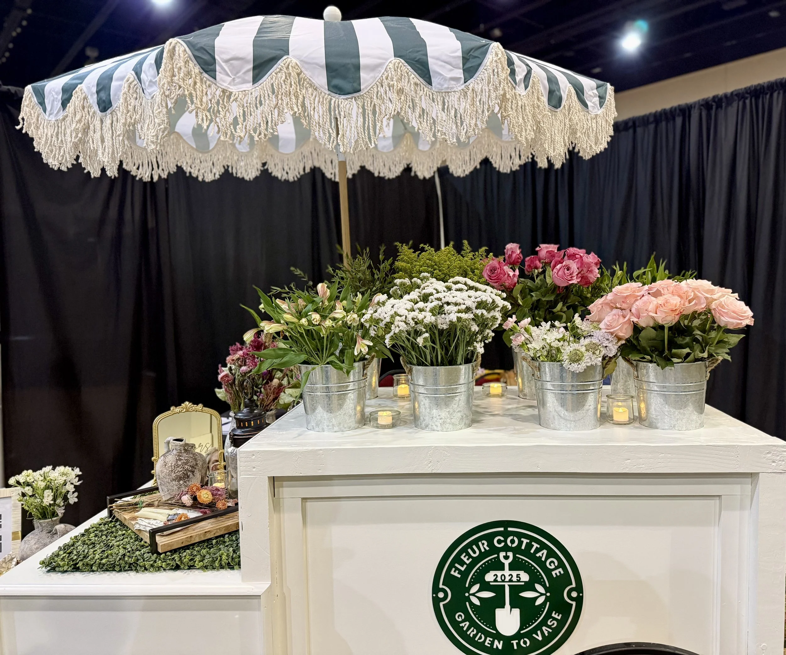 Flower cart with pink and white flowers in metal buckets under a striped green and white umbrella. This flower cart is the perfect addition to your special event - it keeps your guests entertained and provides precious keepsakes.