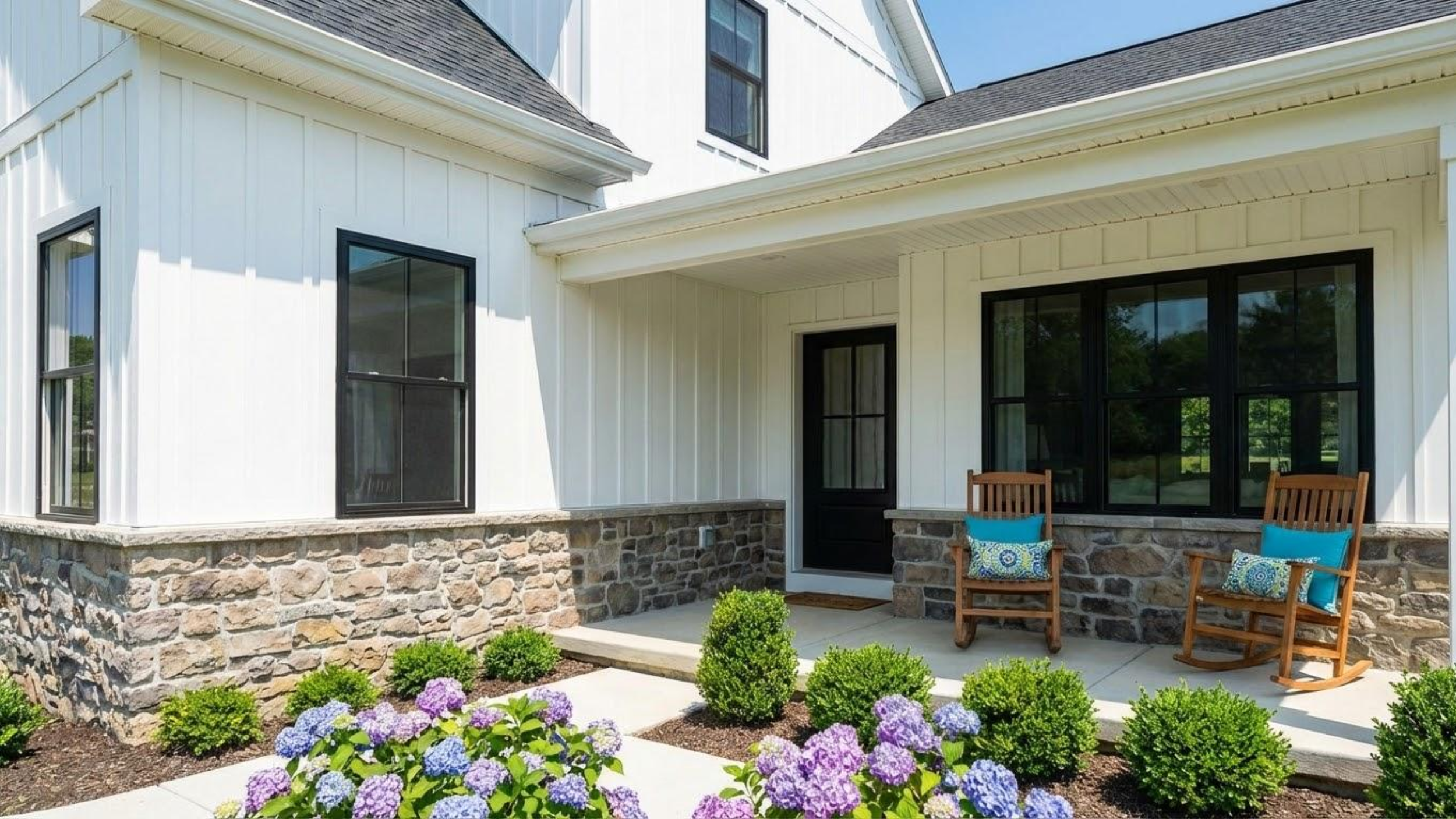 The front porch of a custom new home featuring a stone foundation and black-framed windows, designed by Fresh Start Designs.