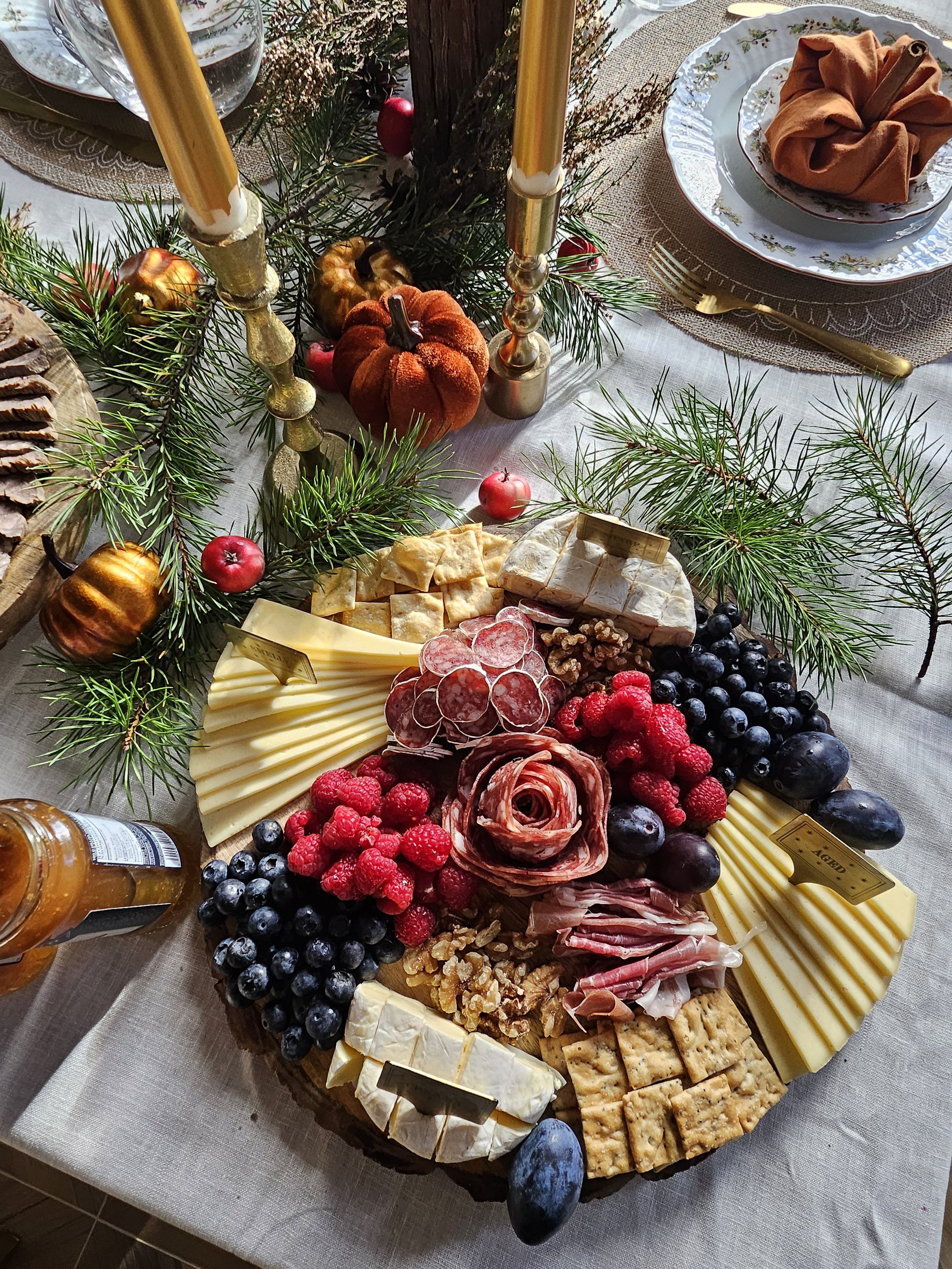 Tarjotin, jossa on erilaisia juustoja, leikkeleitä, hedelmiä ja marjoja.