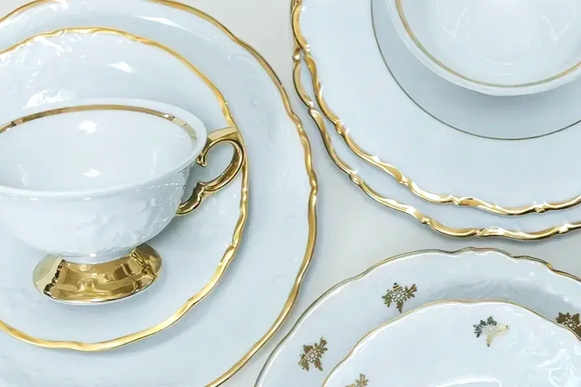 Valkoiset posliinilautaset kultareunuksella, jotka kuuluvat JuhlaToppilan astiavuokraus valikoimaan