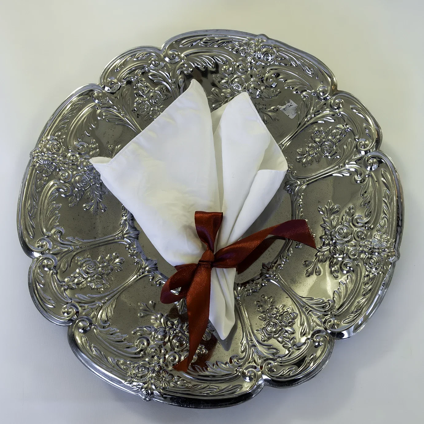 Valkoinen pellavaservetti hopeoidulla tarjottimella JuhlaToppilan astiavuokrauksessa.